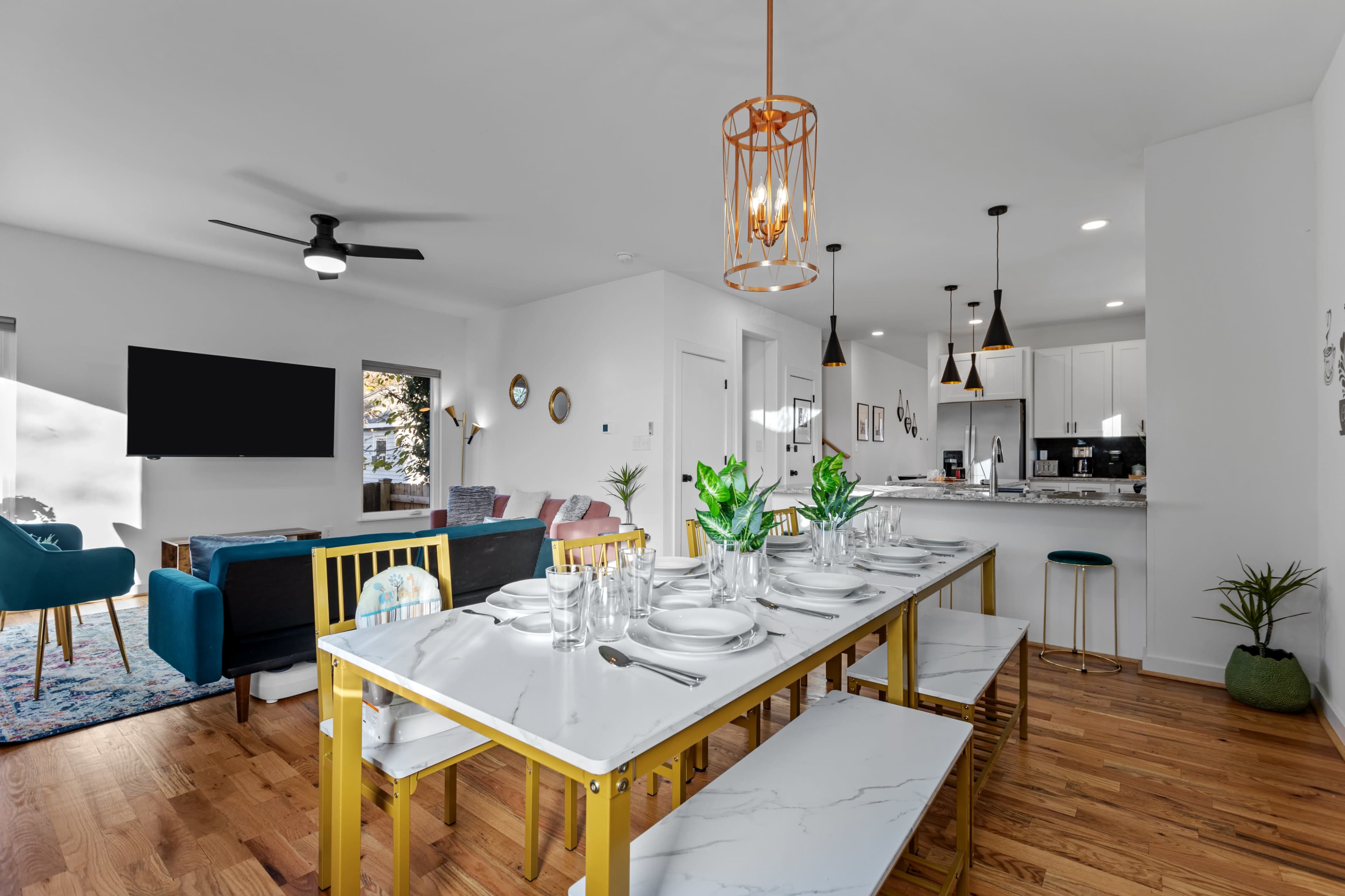 A modern dining room features a marble table set for dinner, surrounded by stylish chairs, with a living area visible through an open space.
