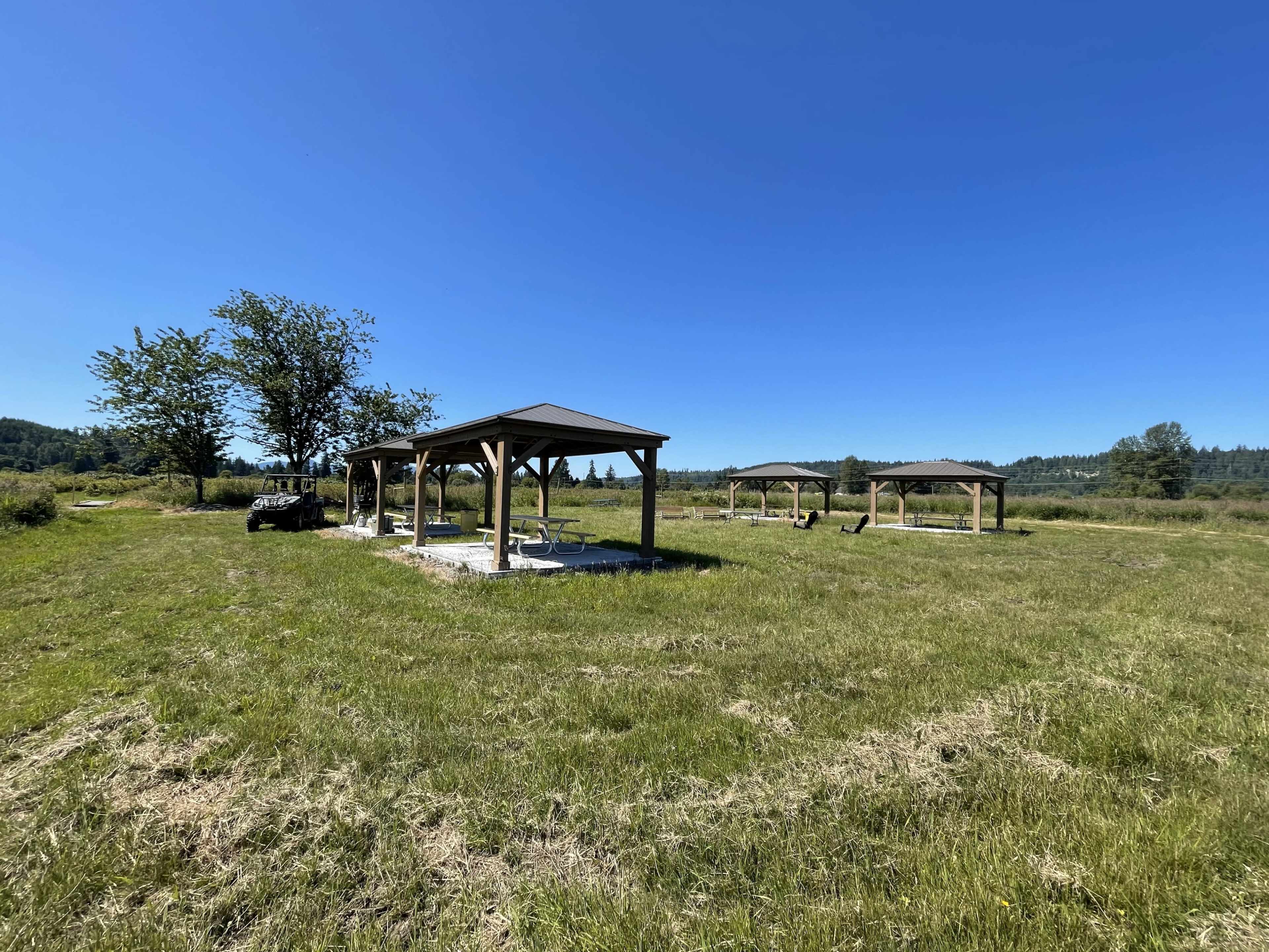 Several wooden shelters on a grassy field under a clear blue sky.