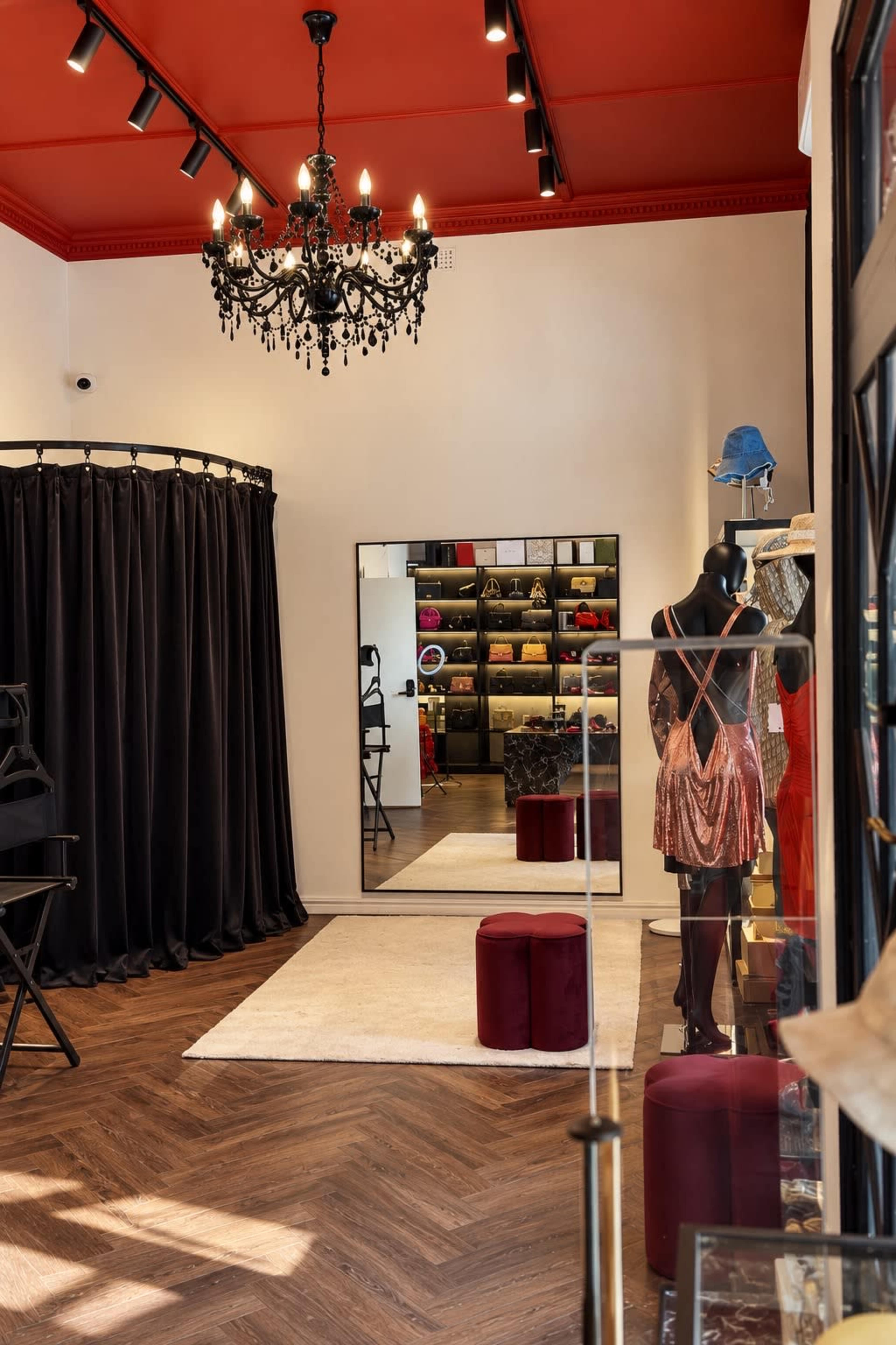 The image shows the interior of a stylish boutique featuring a changing area with black curtains, a large mirror, and a display of clothing on a mannequin.