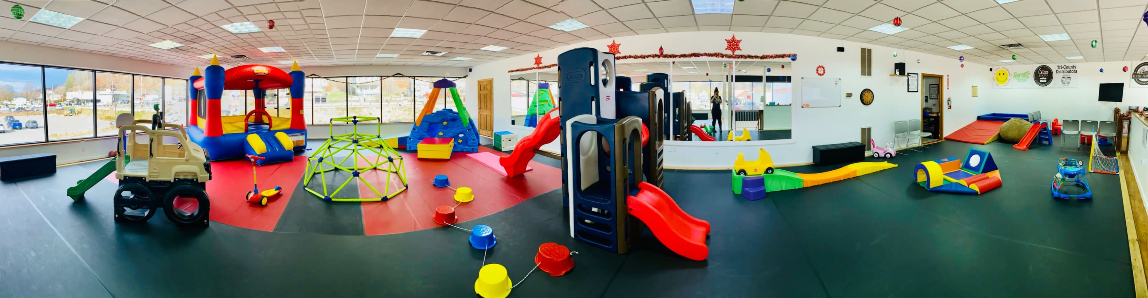 A colorful indoor play area filled with various play structures, toys, and slides.