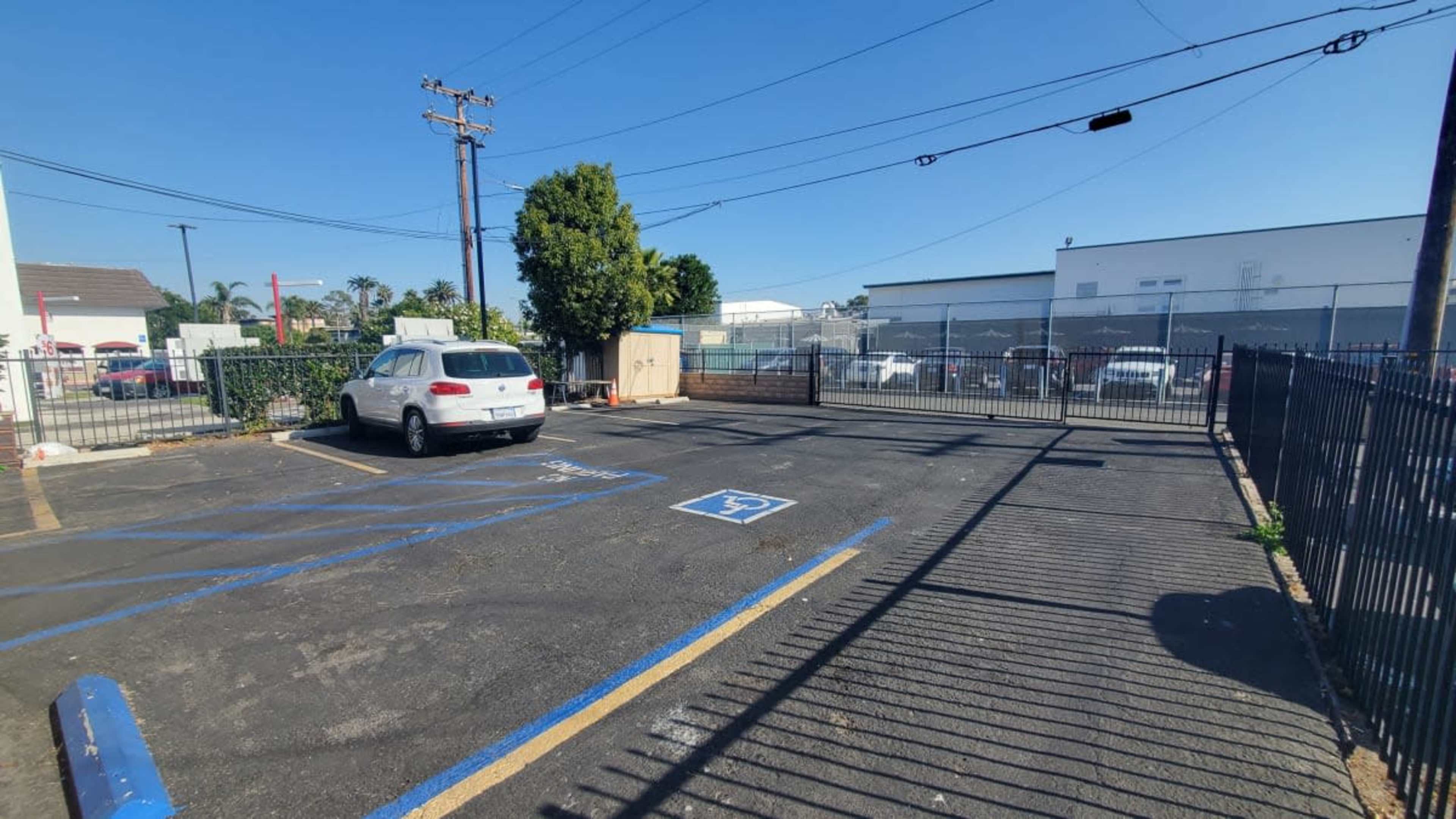 A mostly empty parking lot with marked spaces, including a designated handicapped spot, and a fence in the background.