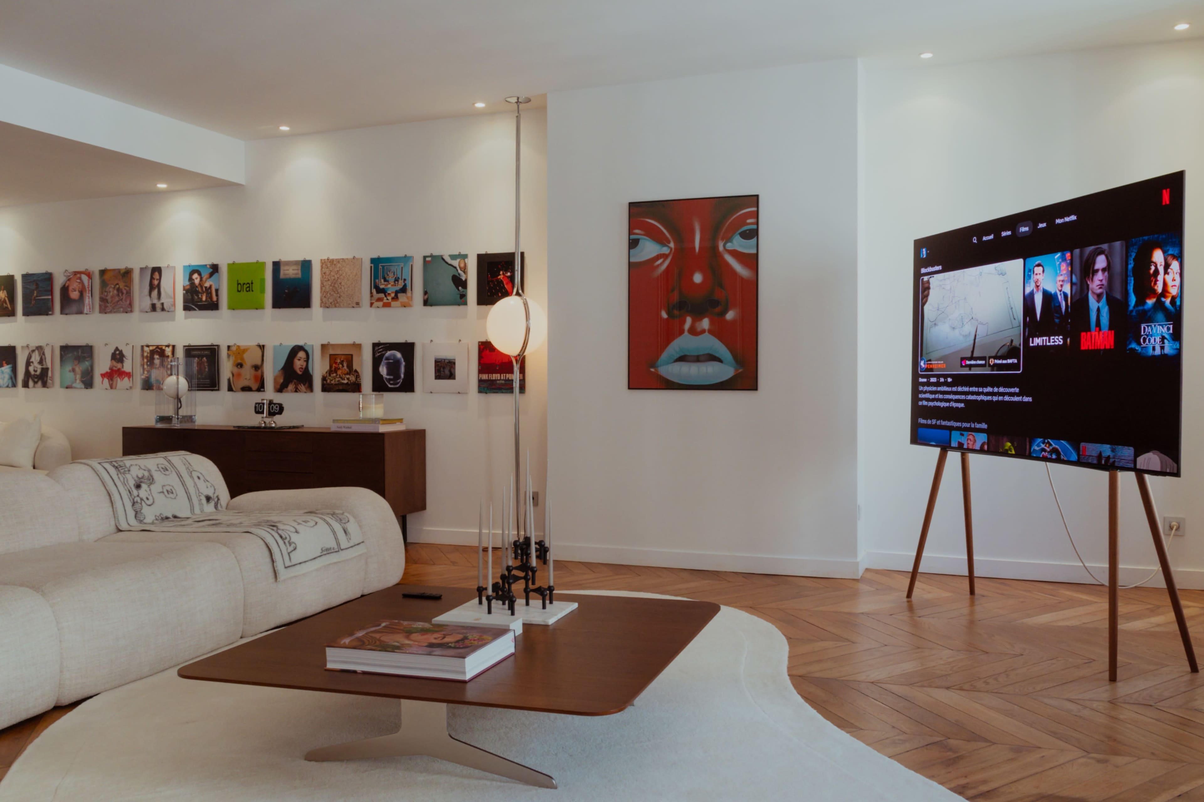 The living room features a modern sofa, a coffee table with a magazine, wall art, and a TV displaying streaming content.