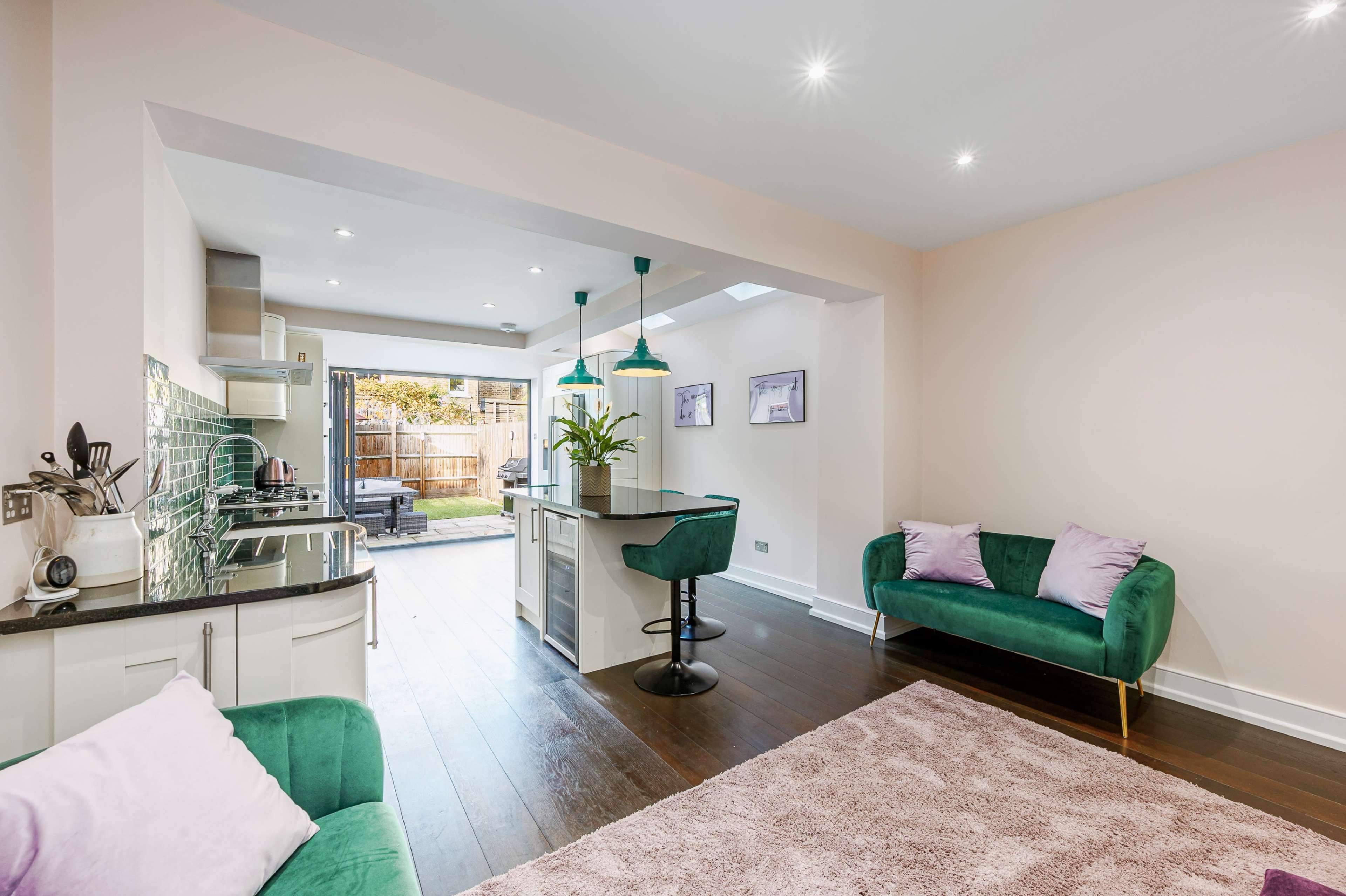 A modern open-concept living space featuring a kitchen, dining area, and a cozy seating area with green velvet furniture.
