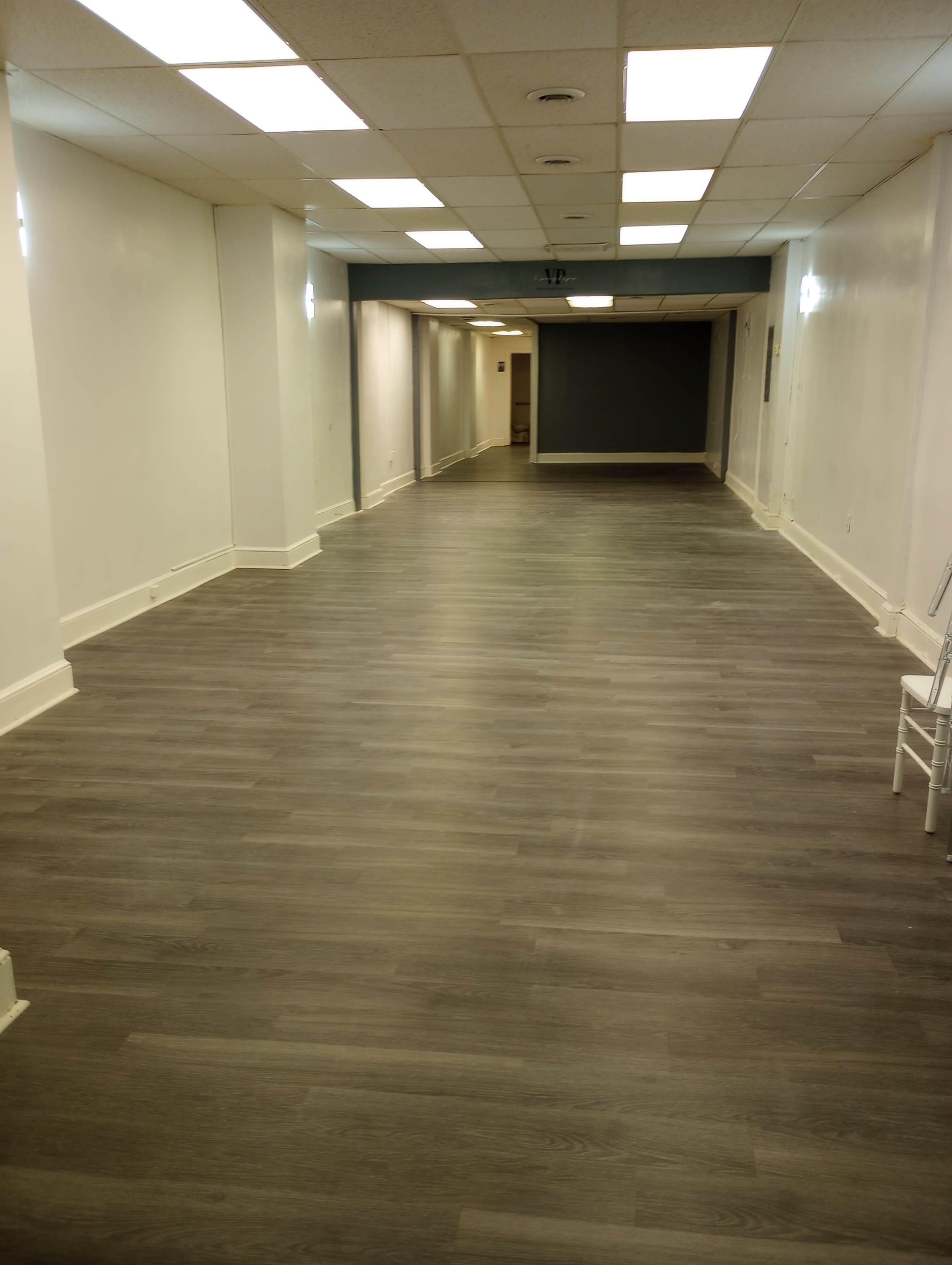 A long, empty hallway with light-colored walls and a wooden floor.