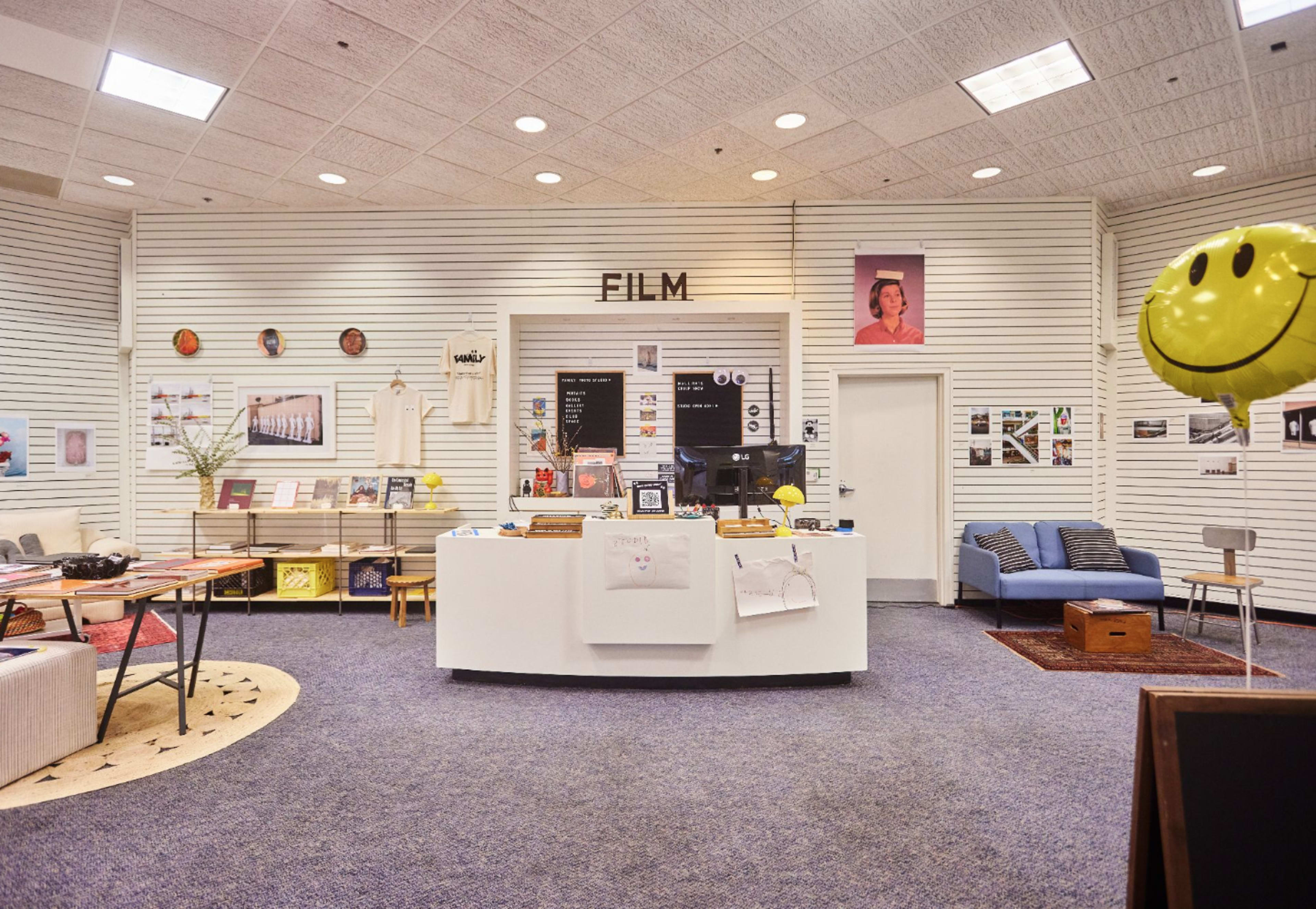 The image shows a modern bookstore or display area focused on film, featuring a white circular counter, bookshelves, and various framed images on the walls.