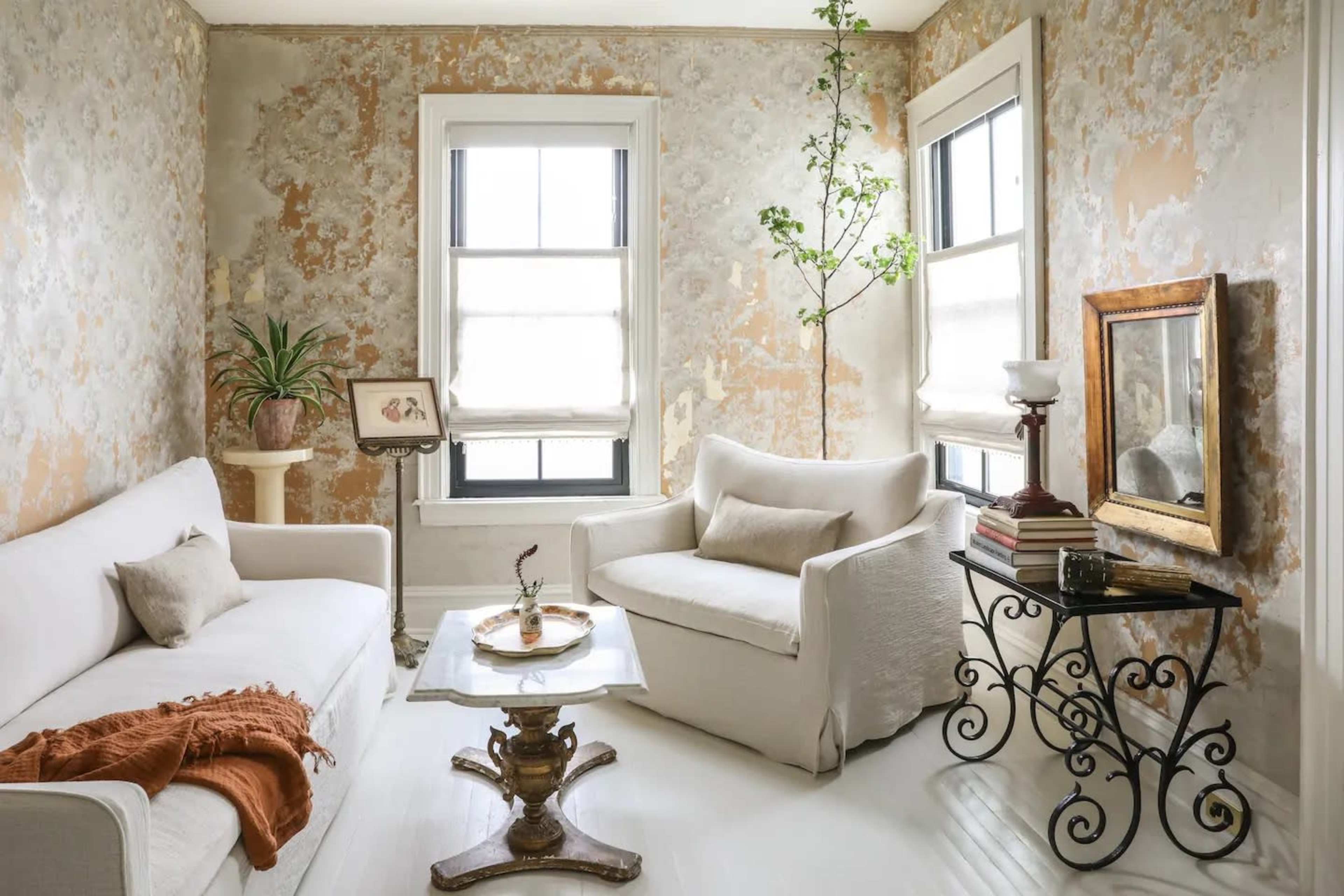 A living room with two sofas, a coffee table, a small plant, and walls adorned with textured wallpaper.
