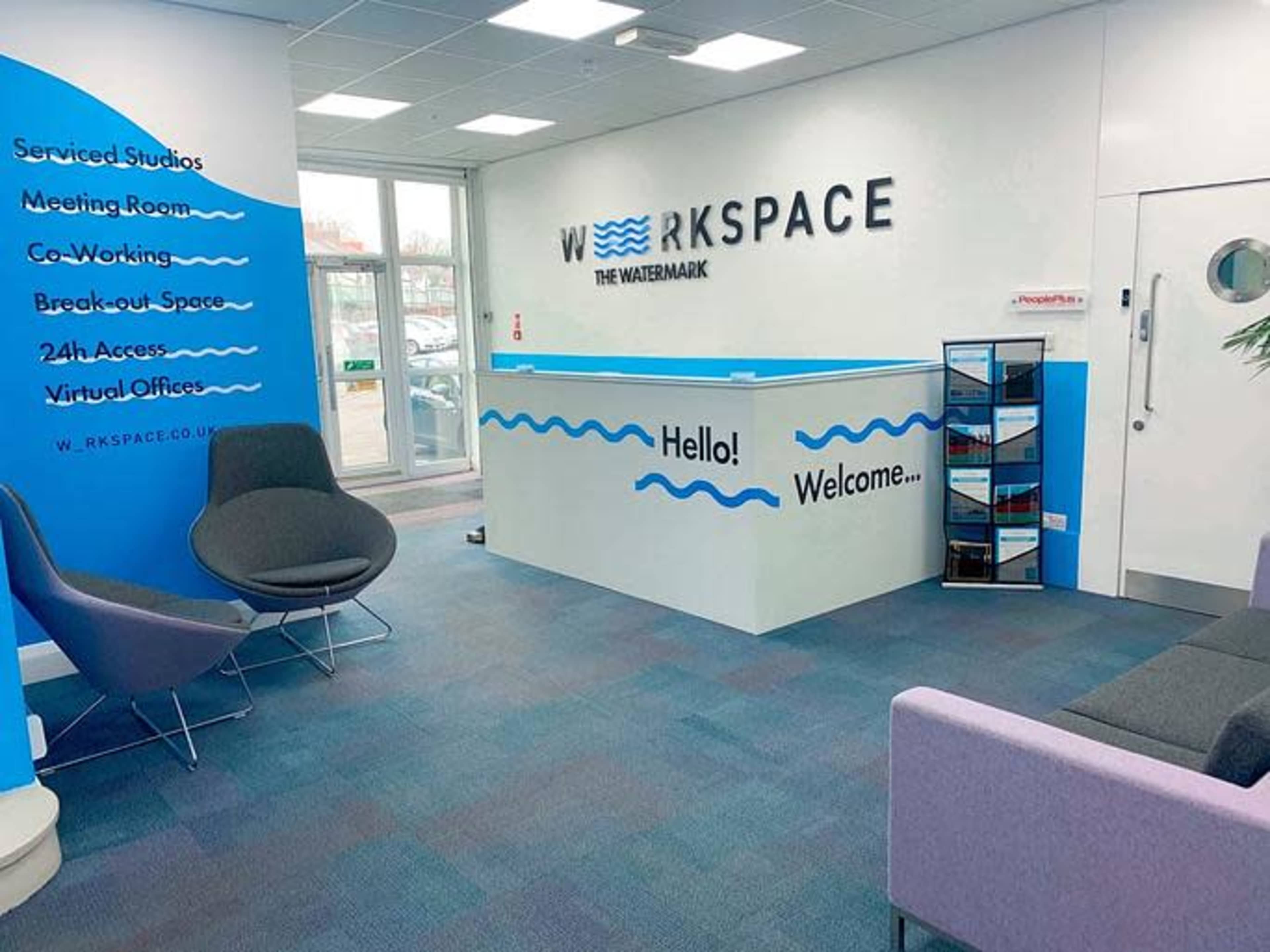 The image shows a modern reception area with a blue and white color scheme, featuring a front desk that displays the name "WORKSPACE" and seating arrangements.