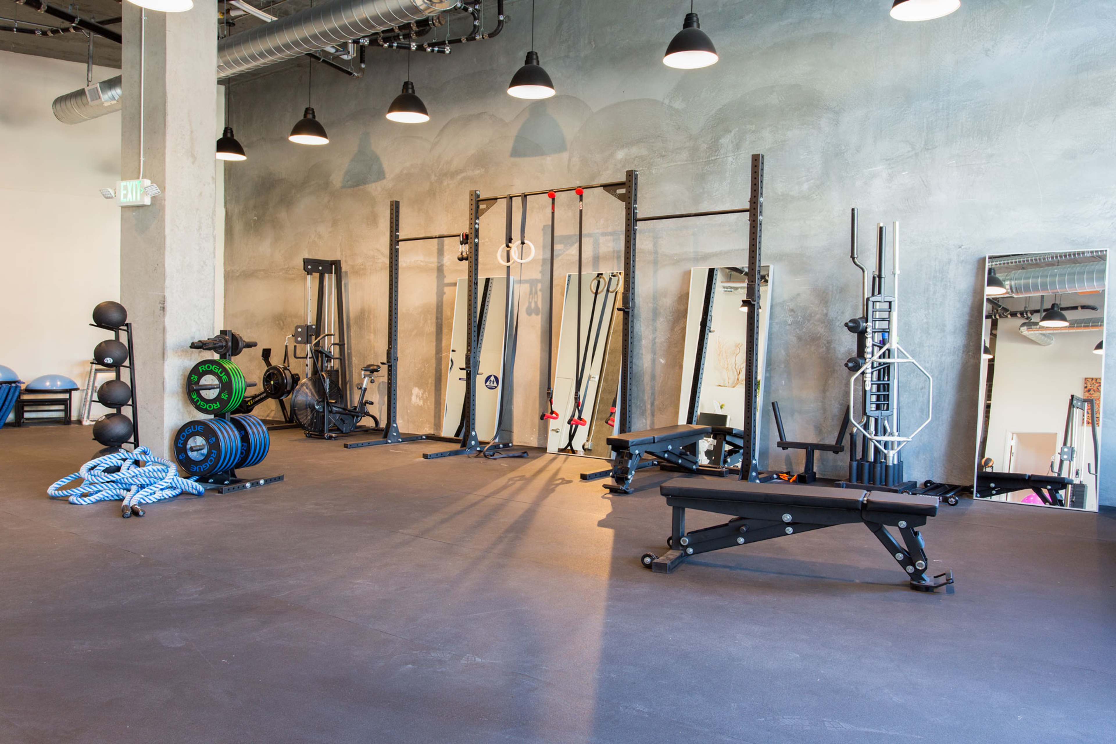 A spacious gym interior equipped with various workout equipment, including weights, benches, and resistance bands.
