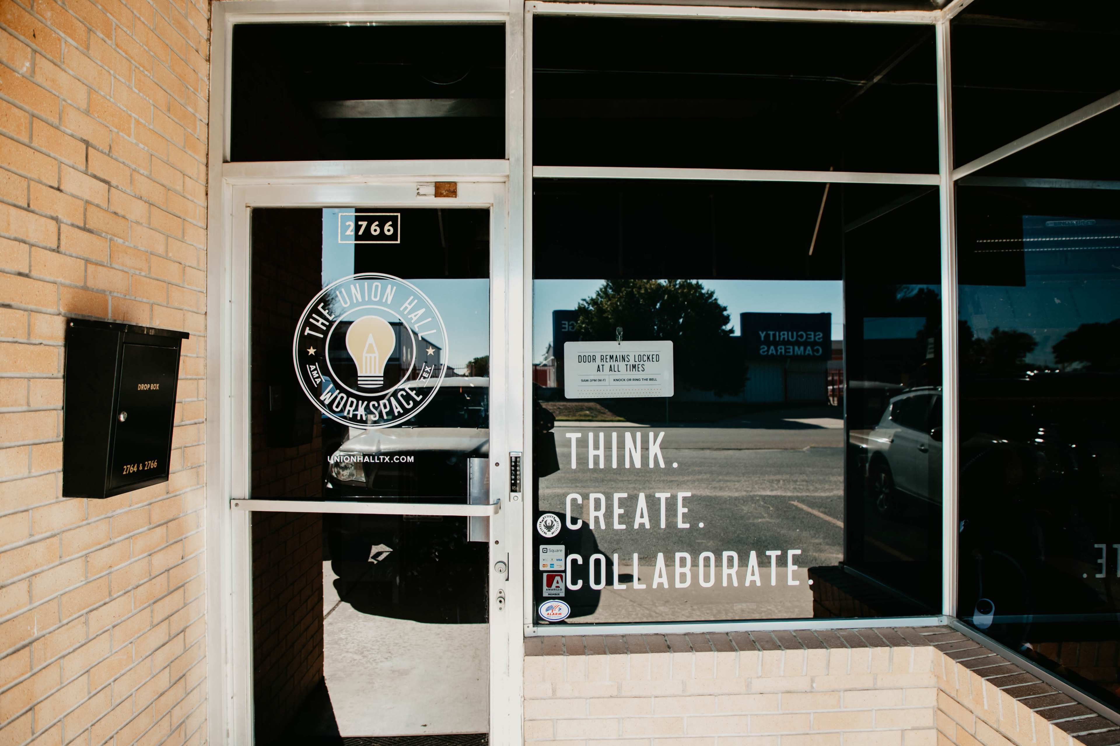 The entrance of The Union Mill workspace, featuring a glass door with the logo and a sign that reads "Think. Create. Collaborate."