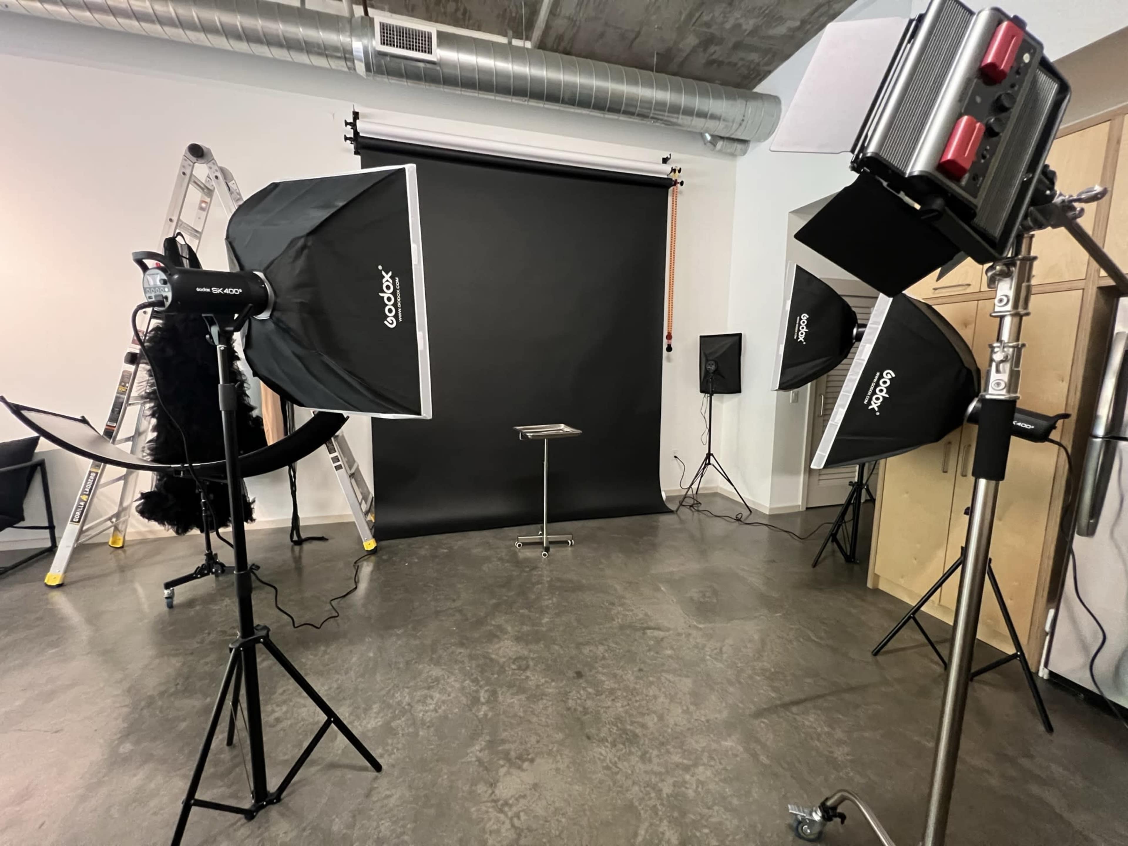 A photography studio setup with a black backdrop, lighting equipment, and a table in the center.