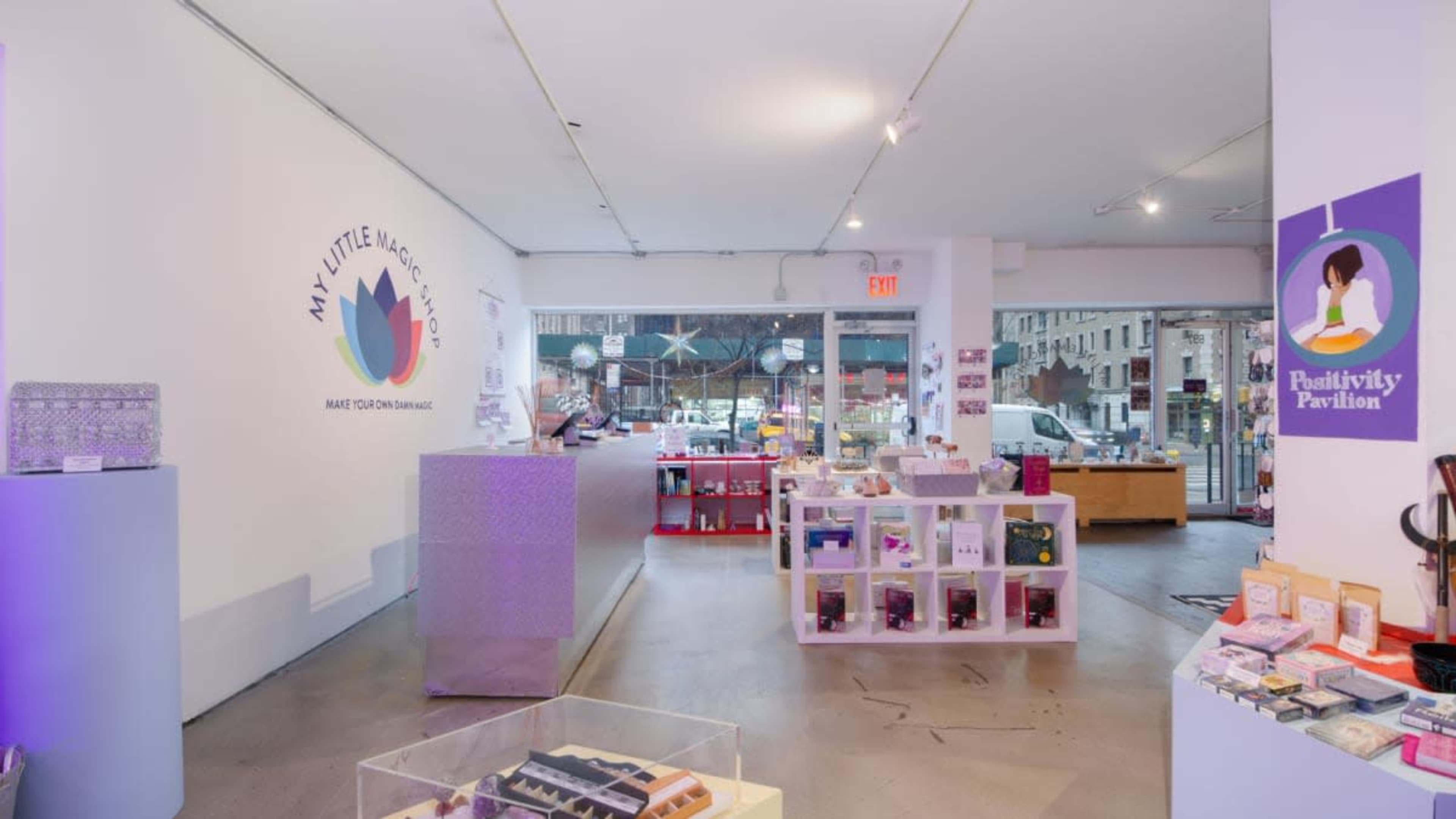 The image shows the interior of a brightly lit store with a reception area, product displays, and large windows facing a street.