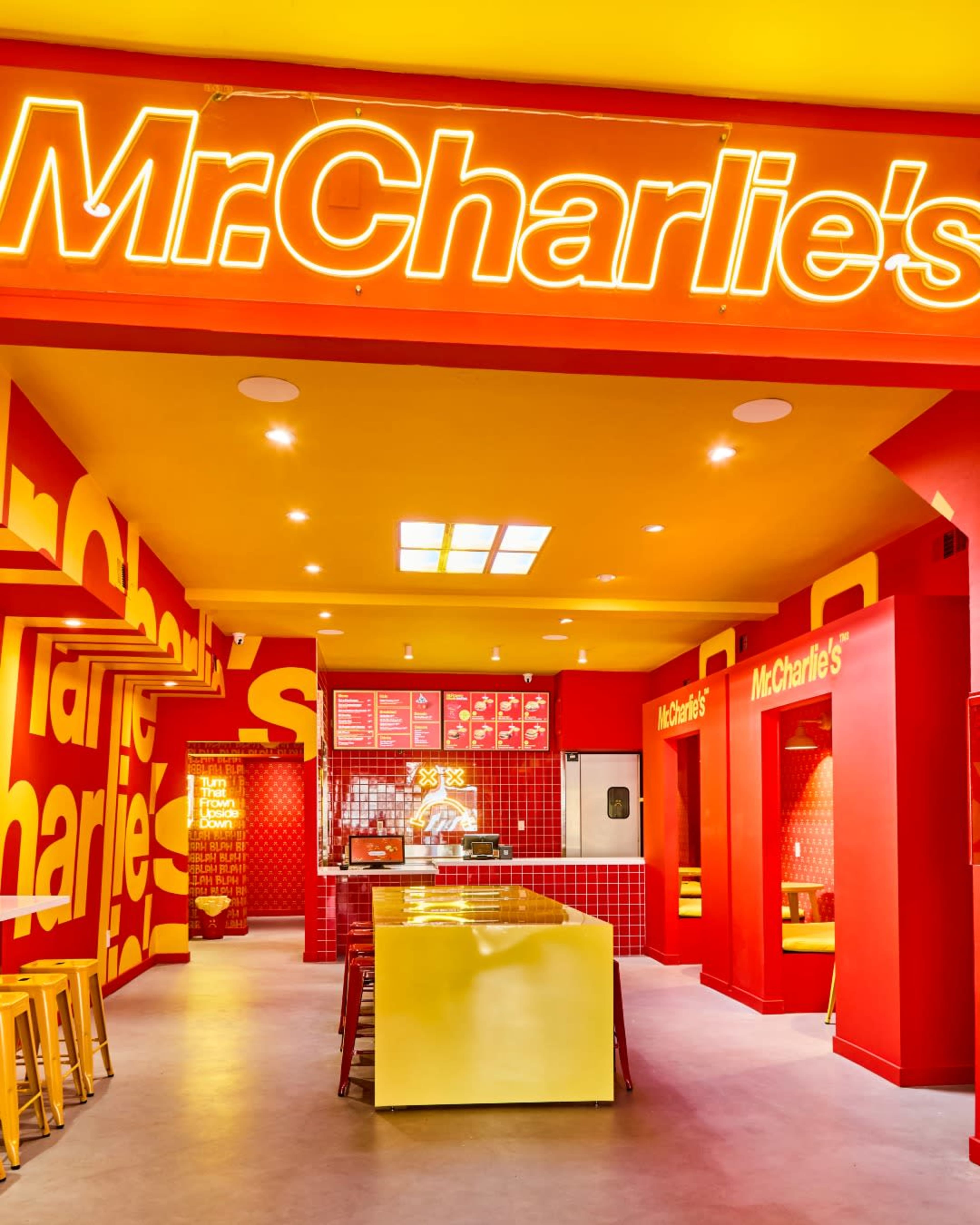 The image shows a brightly colored fast-food restaurant interior with red and yellow décor, featuring the name "Mr. Charlie's" prominently displayed on the wall.