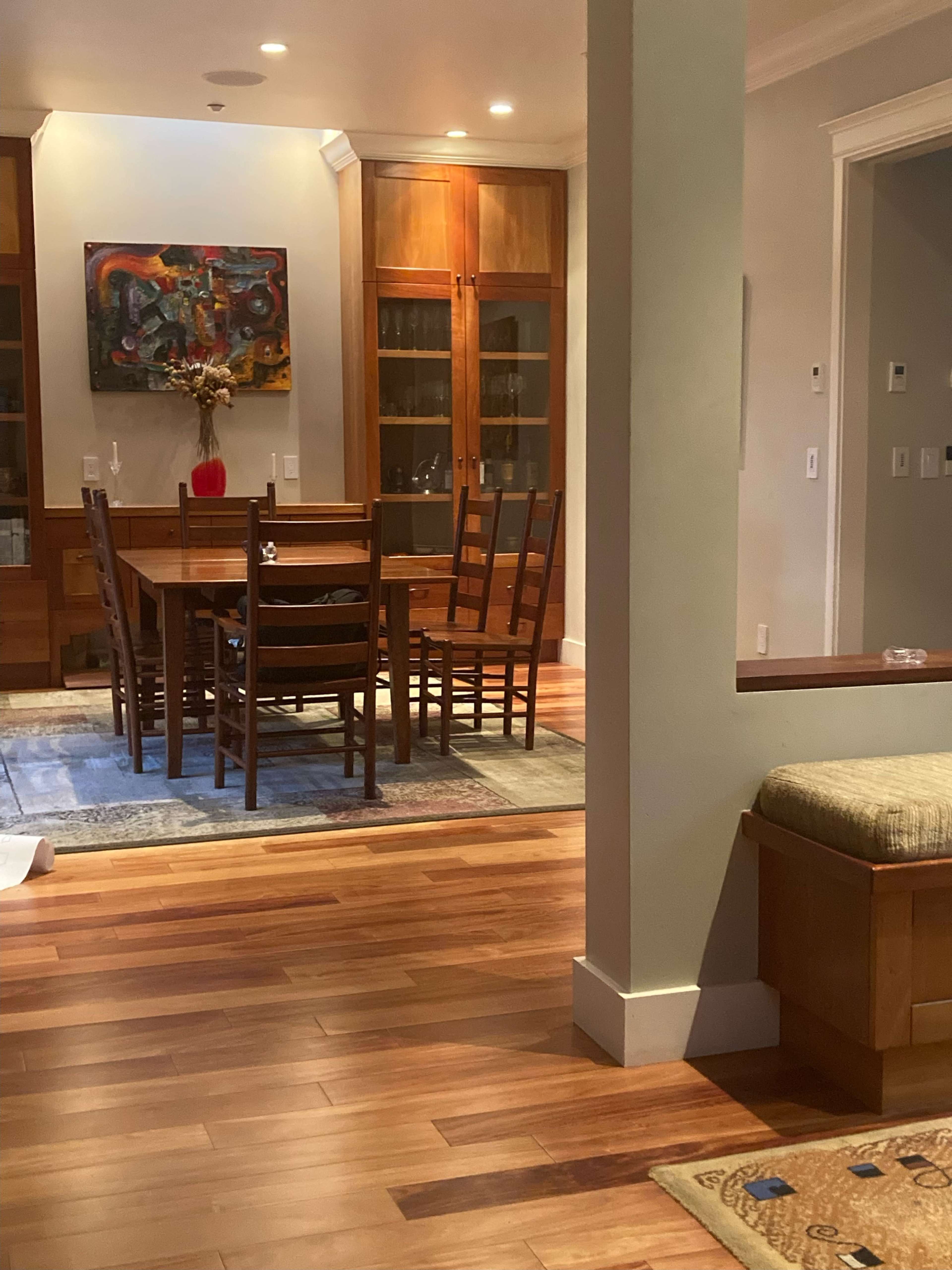 A dining area with a wooden table and chairs, surrounded by glass-front cabinets, and a decorative piece on a side table.
