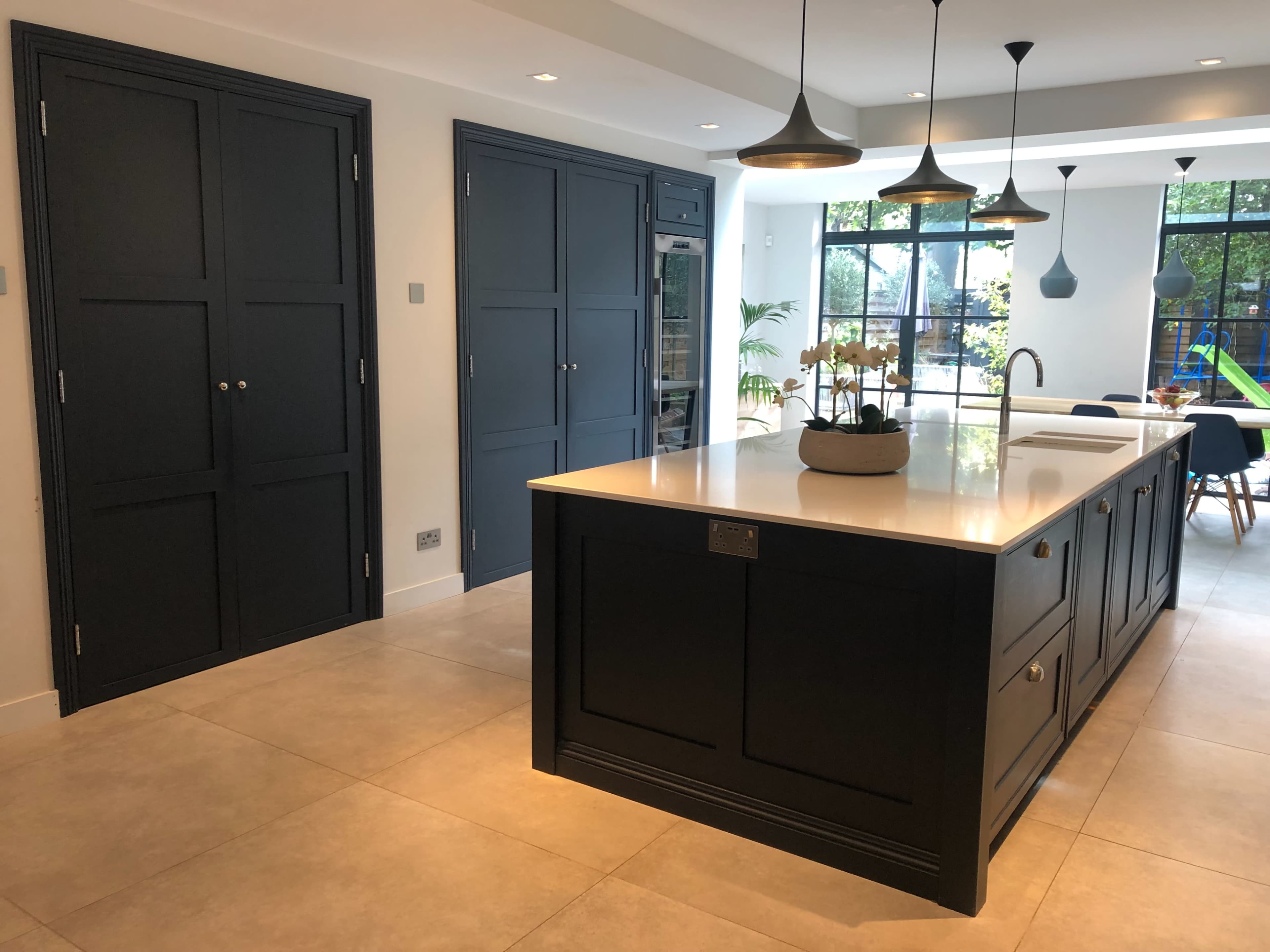 The kitchen features dark cabinetry, a large island with a white countertop, and modern pendant lighting above.