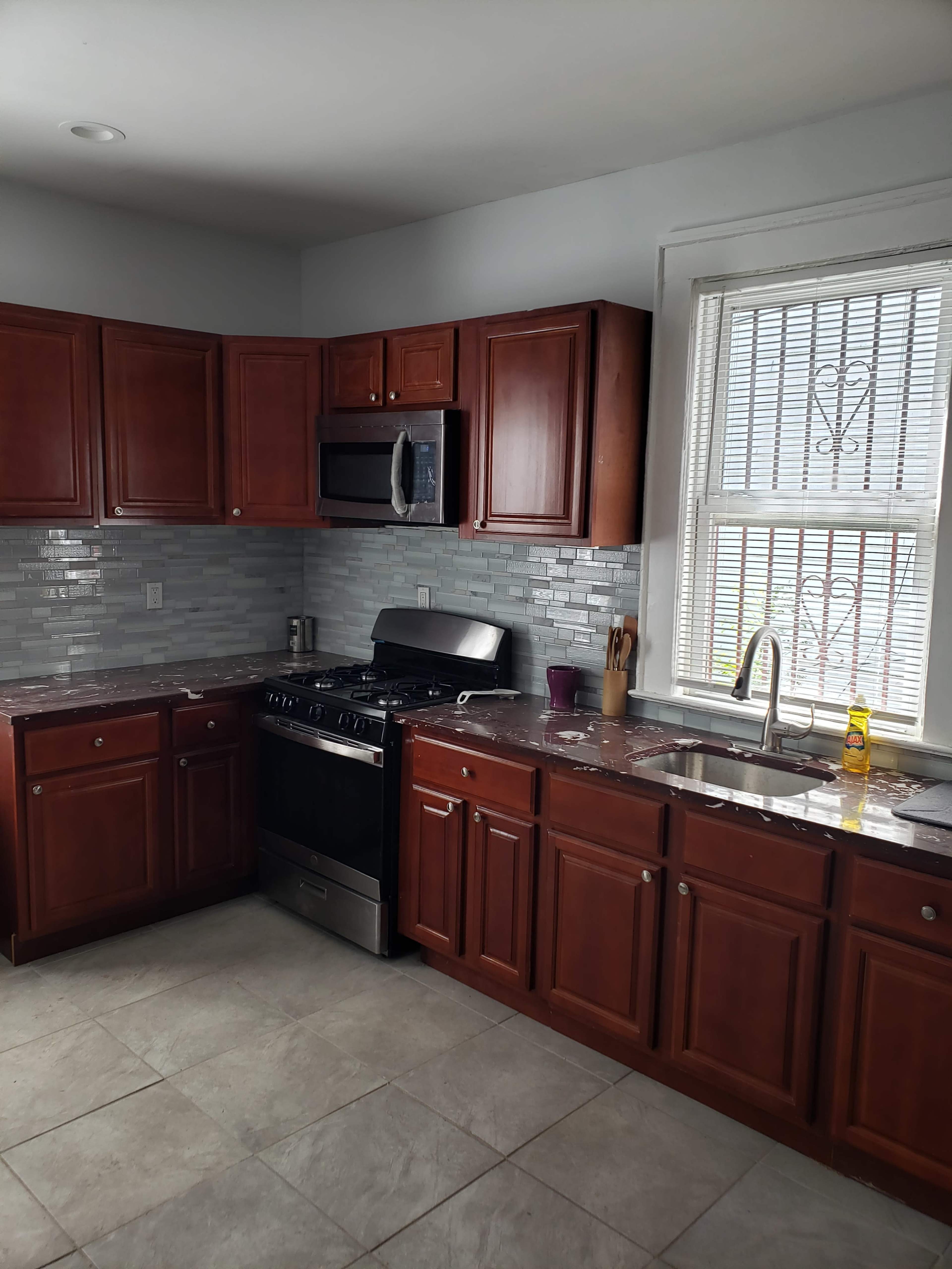 A modern kitchen with wooden cabinets, stainless steel appliances, and a tiled backsplash.