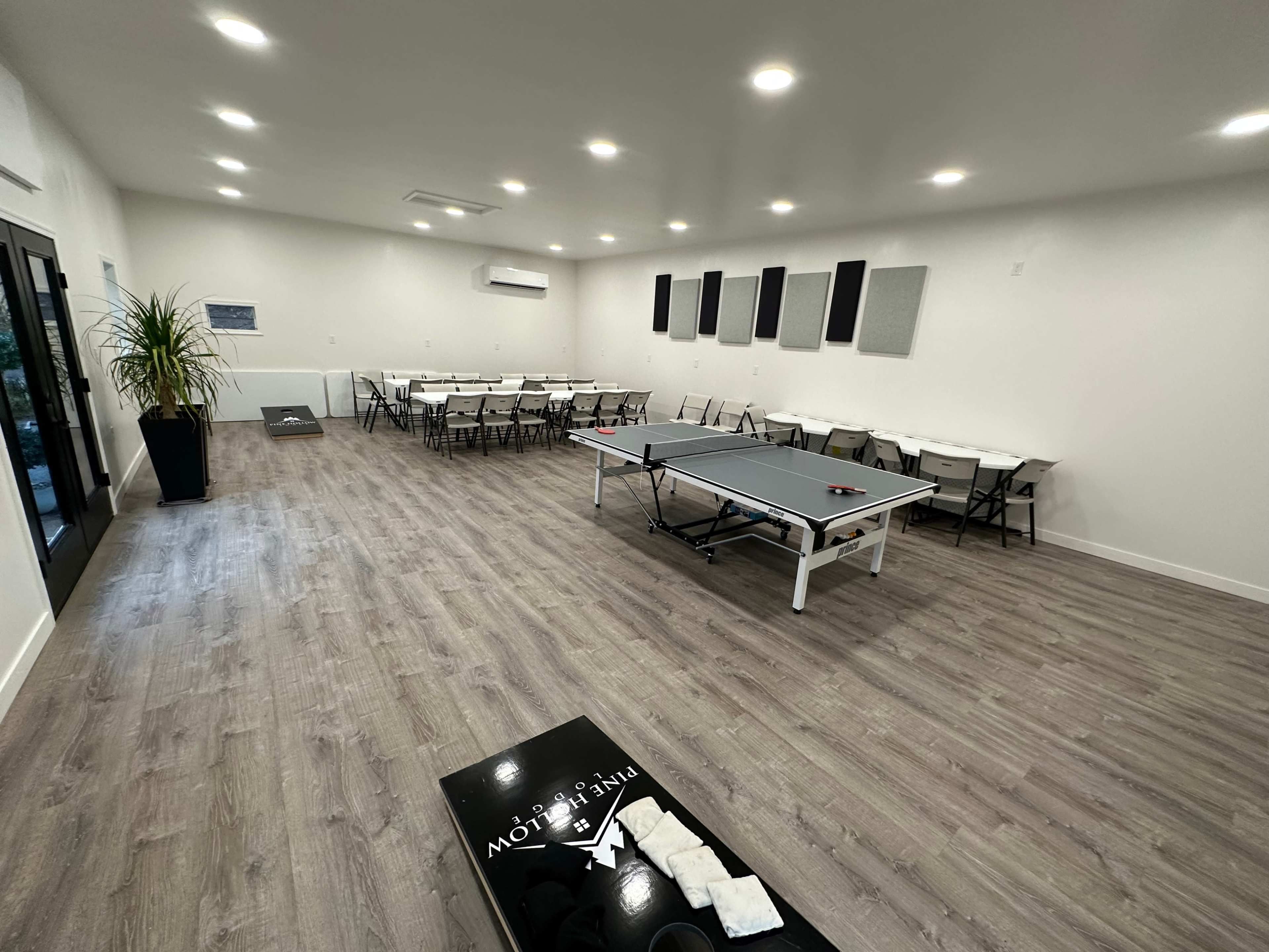 A spacious room with a ping pong table, surrounded by tables and chairs arranged for an event.