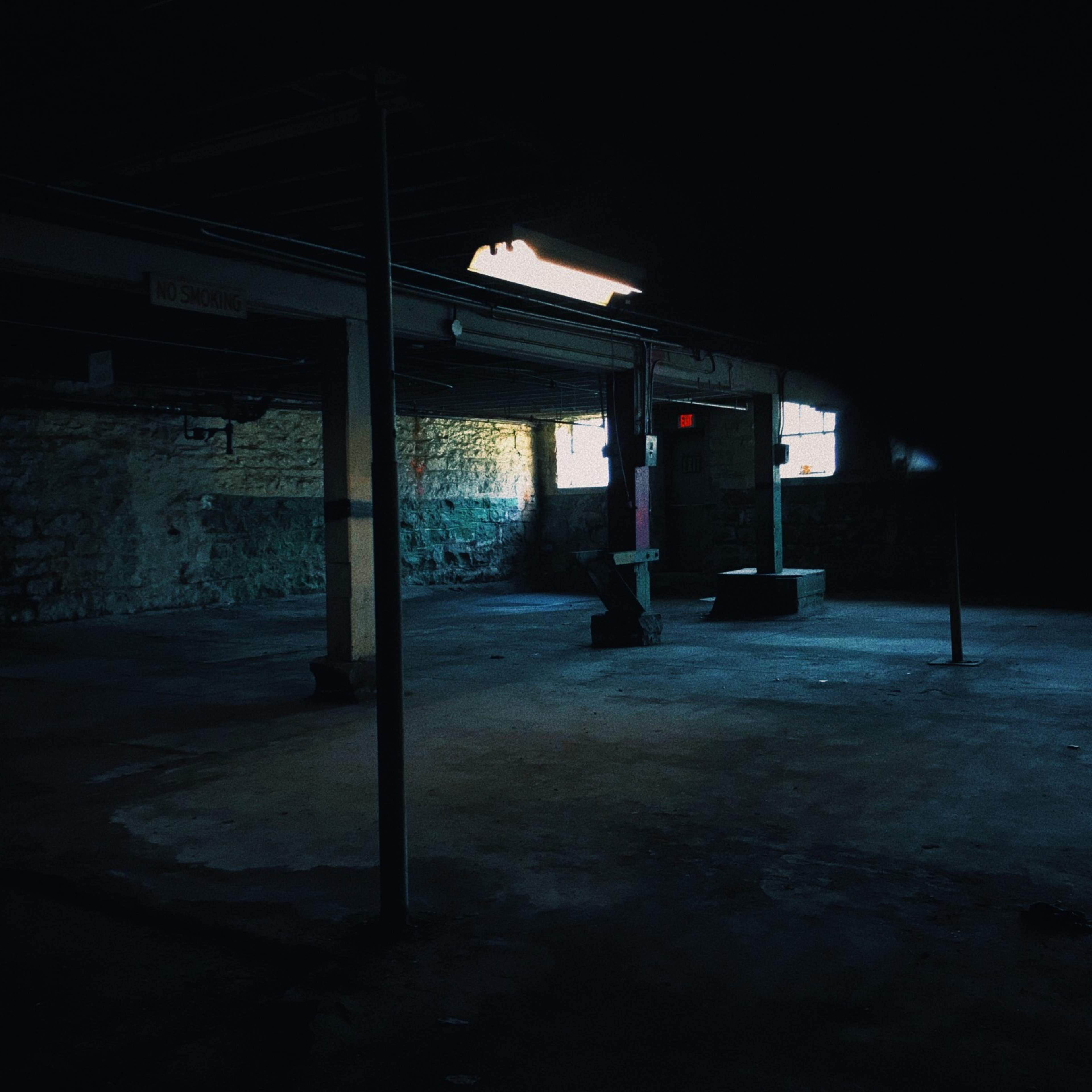 An empty, dimly lit industrial space with exposed stone walls and a few windows.