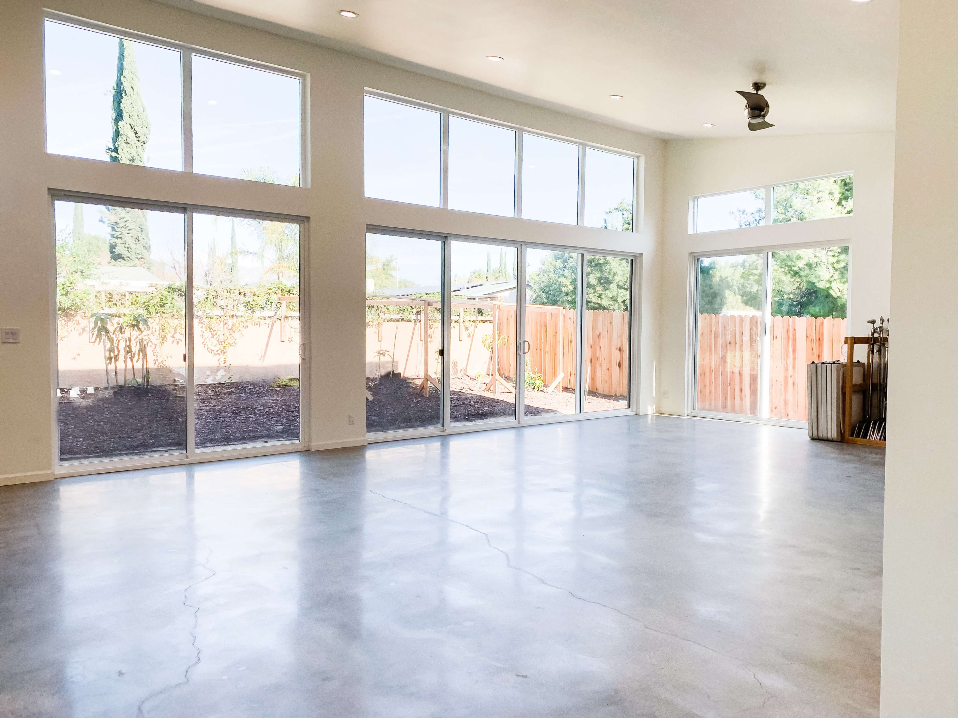 A large, open interior space features concrete flooring and multiple floor-to-ceiling windows that provide ample natural light.