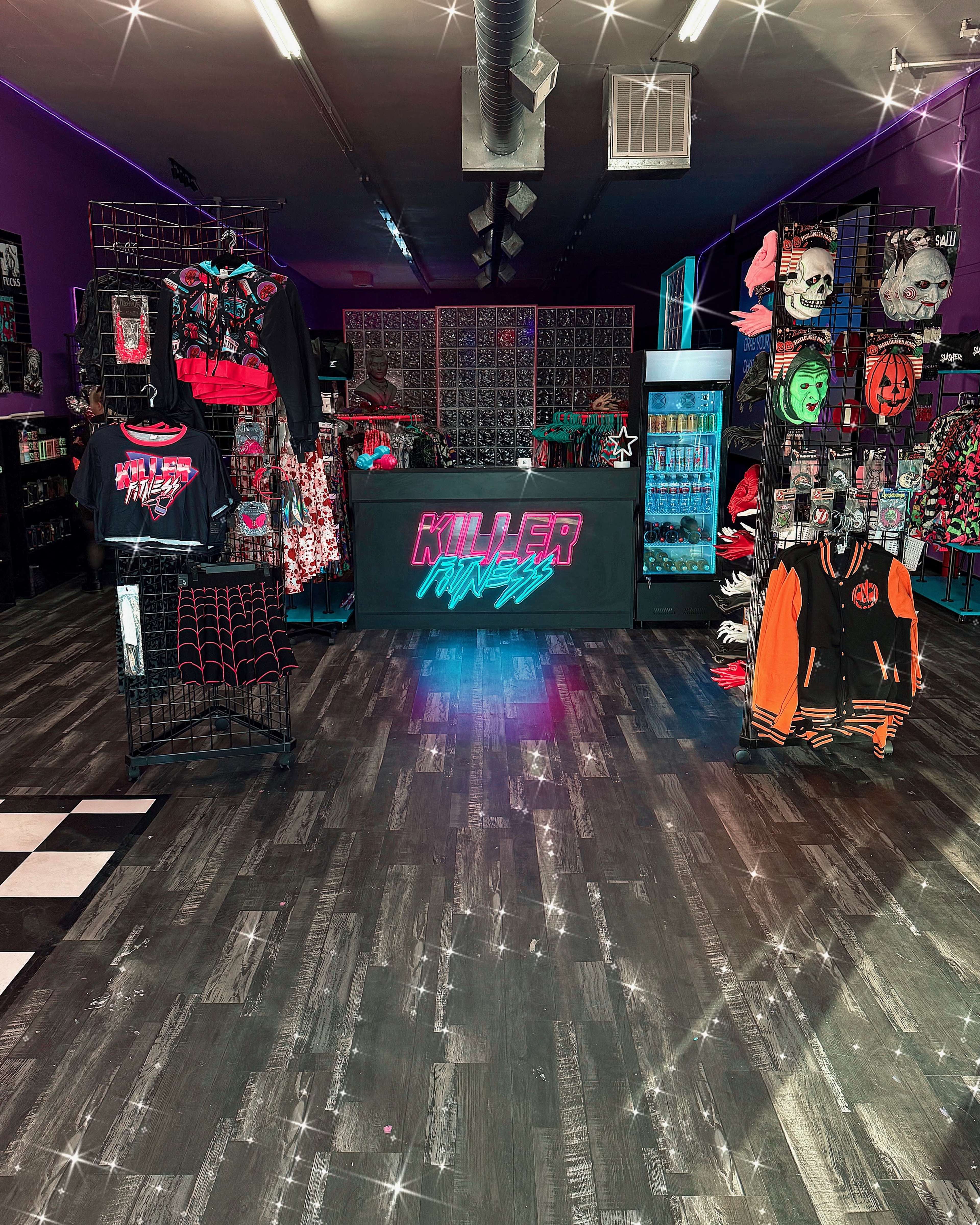 A brightly lit retail store features a display of clothing and accessories with a horror theme, including graphic tees, hoodies, and various decorative items.