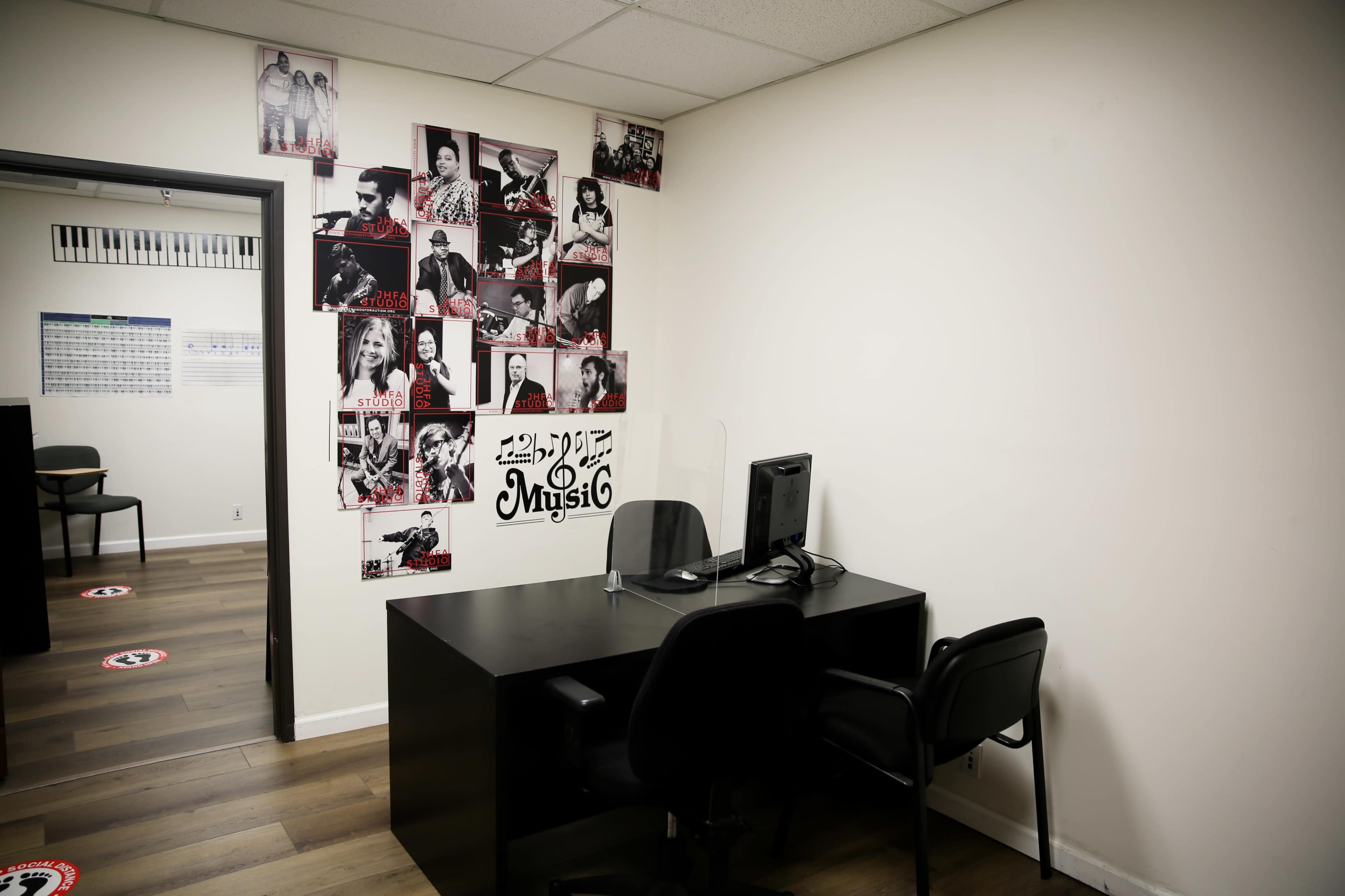 A small office space with a desk, two chairs, and walls decorated with black-and-white photos of musicians.