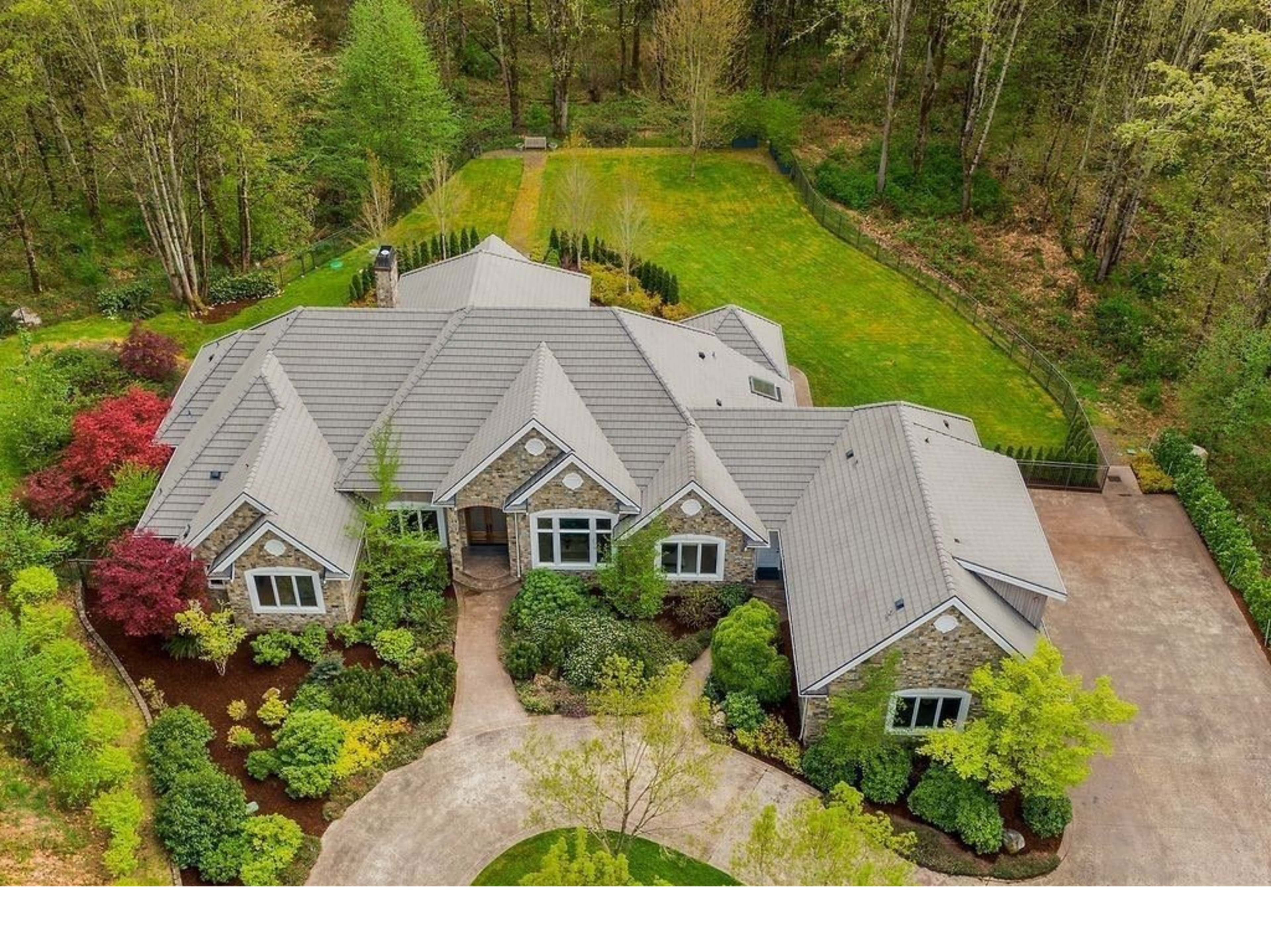 The image shows a large, landscaped residential home surrounded by greenery and trees.