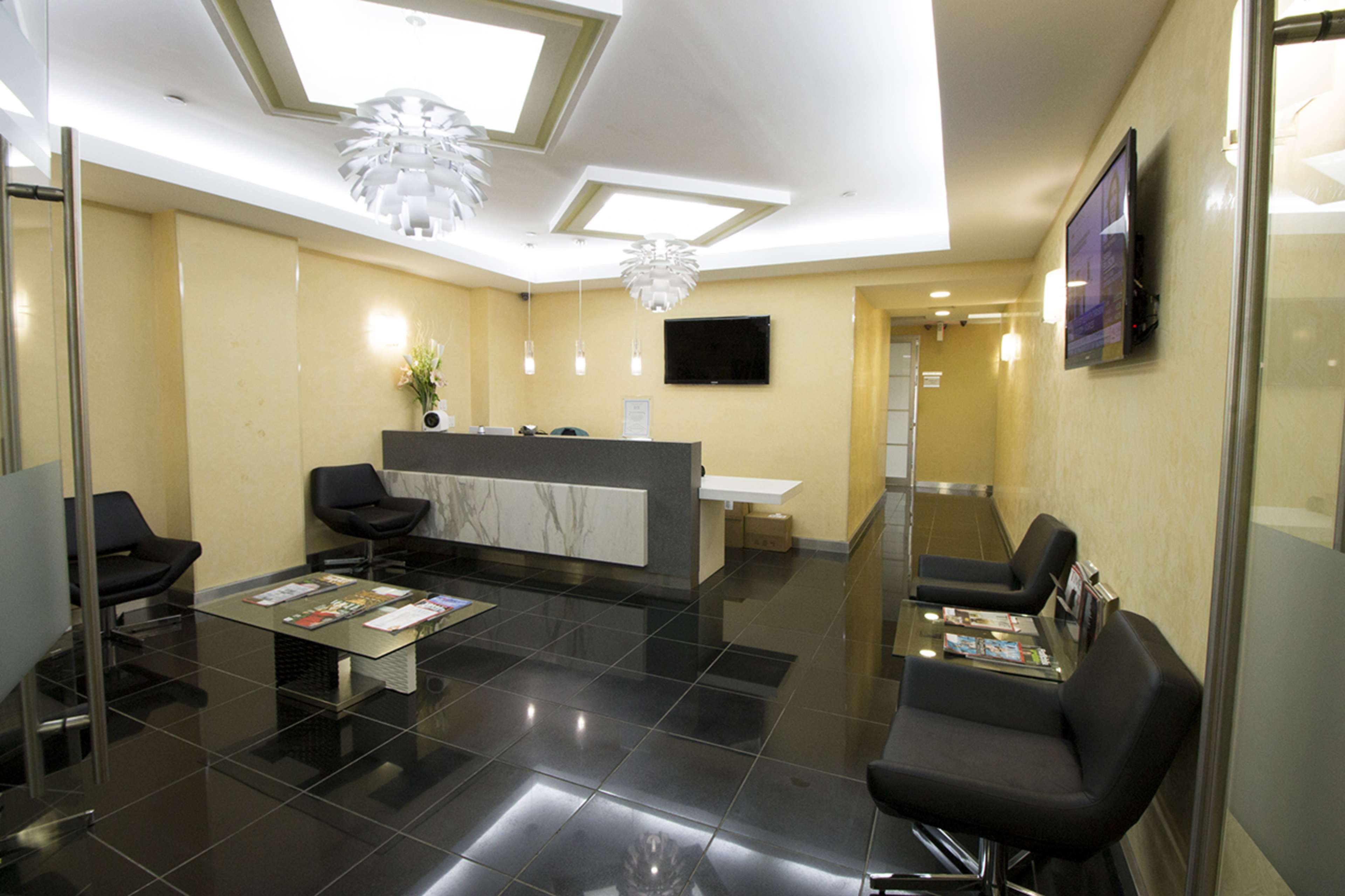 The image shows a modern reception area with black tiled flooring, a marble counter, glass partitions, and contemporary seating arrangements.