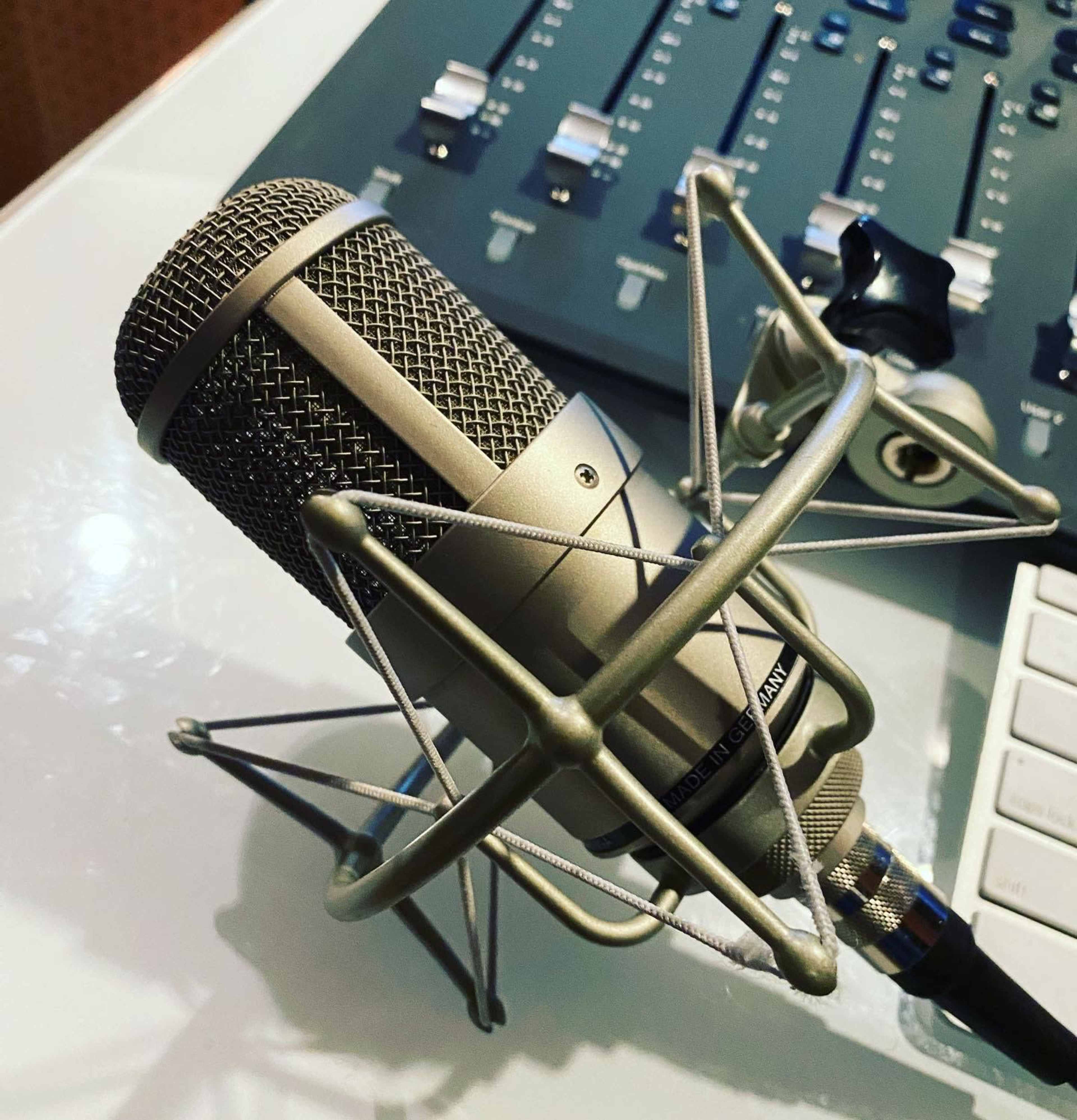 A microphone is positioned on a table beside audio mixing controls.