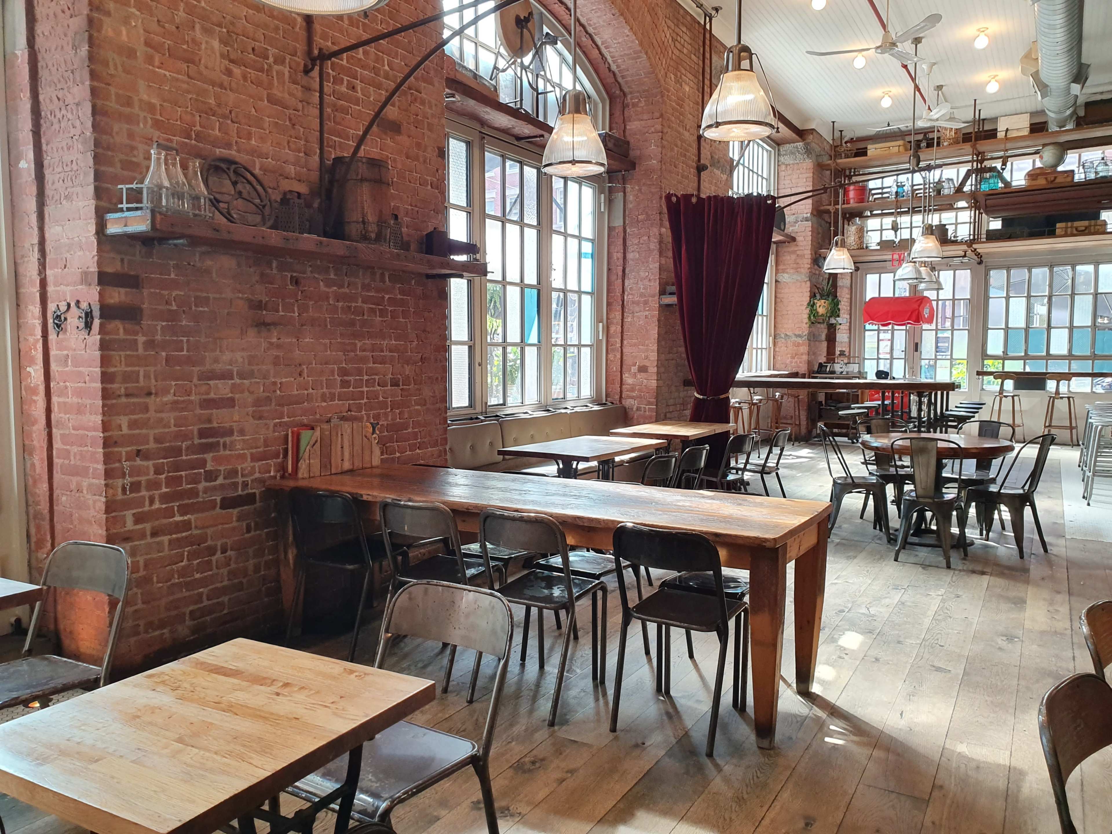 A rustic restaurant interior with exposed brick walls, wooden tables, and metal chairs.