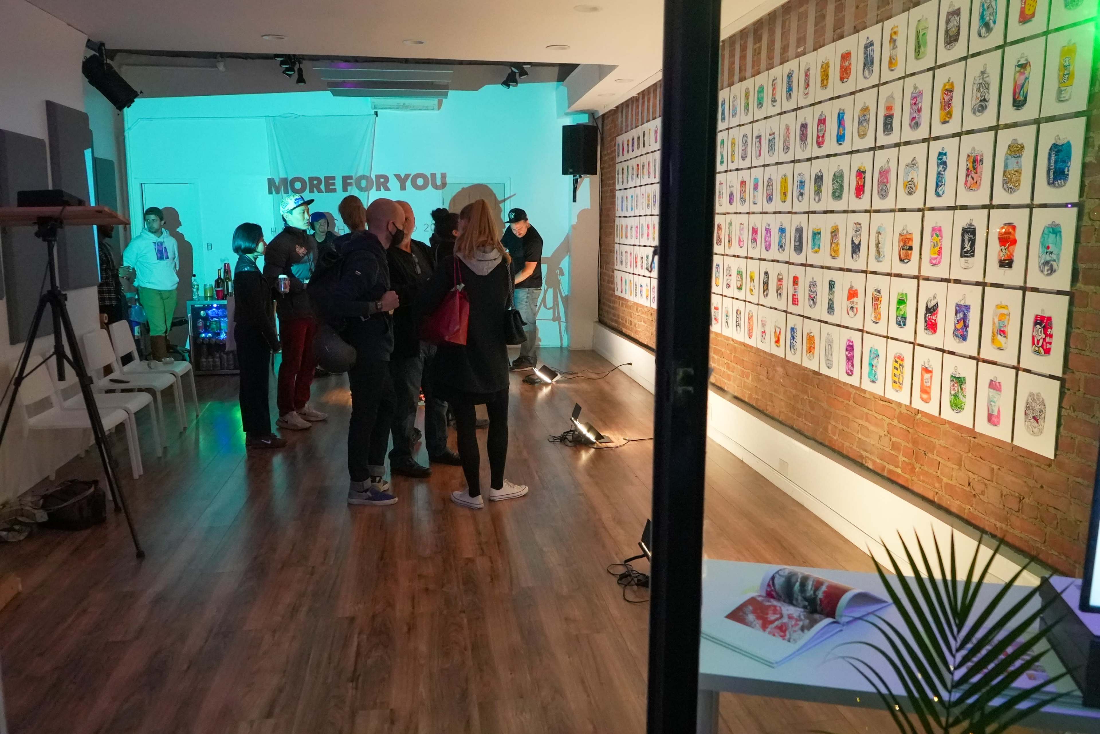 A gathering of people in a room showcasing a collection of colorful art pieces on the walls.