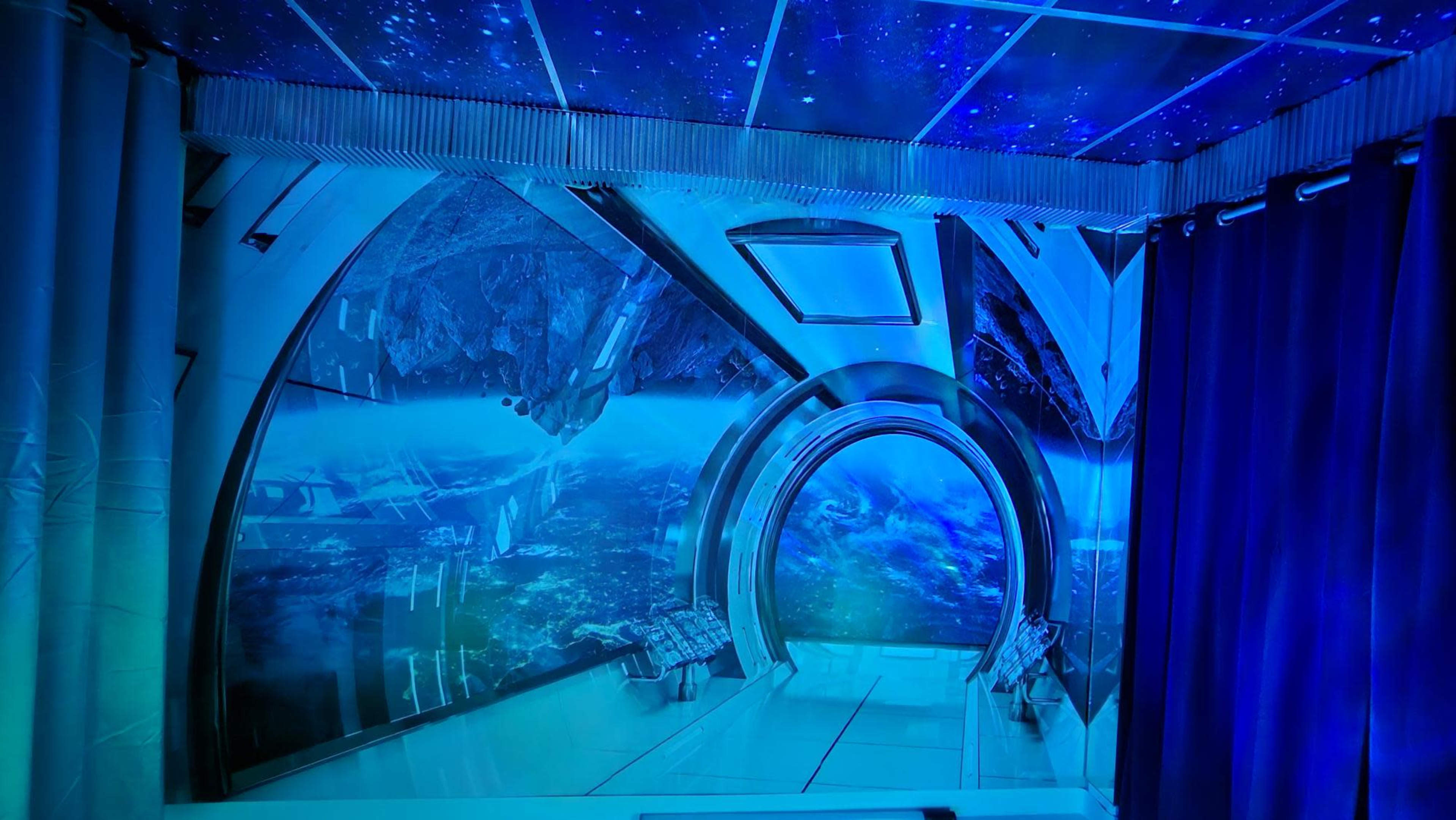 A futuristic room with a large circular window overlooking a starry space scene and sleek, metallic architecture.
