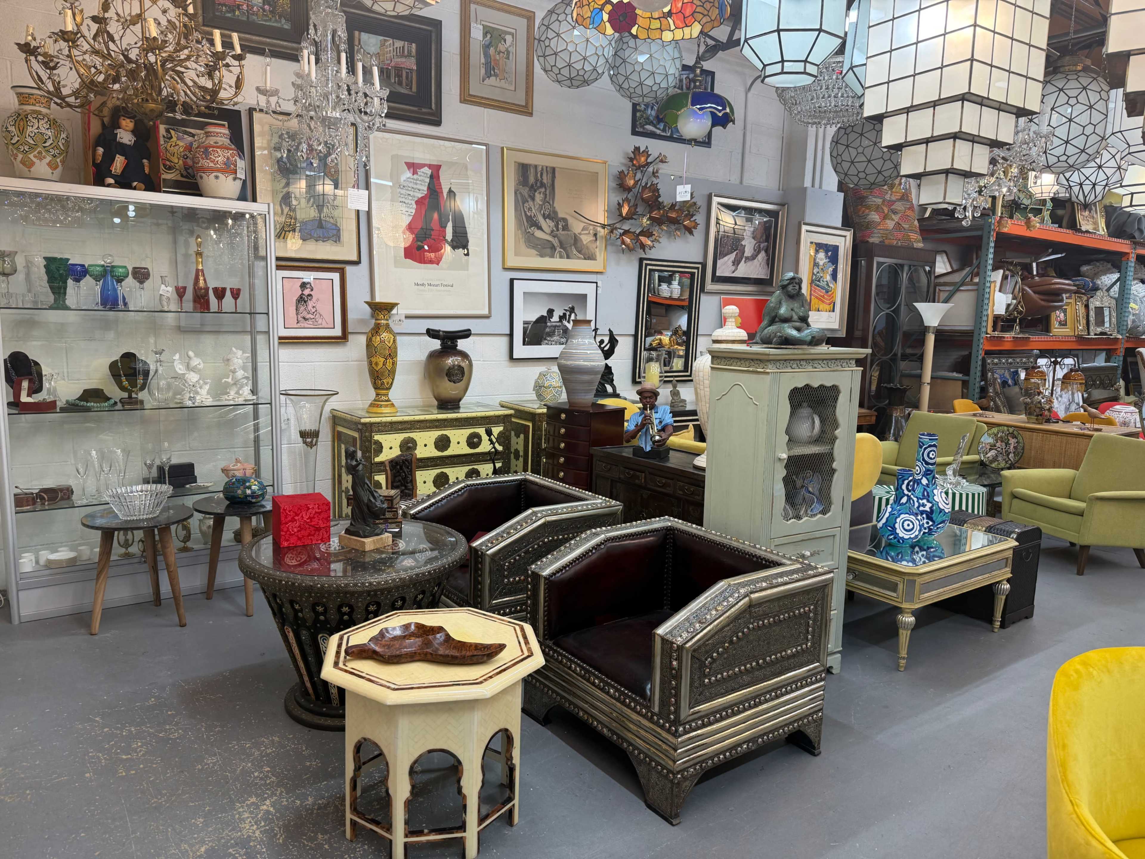 The image displays a spacious antique shop filled with a variety of vintage furniture, decorative items, and wall art.