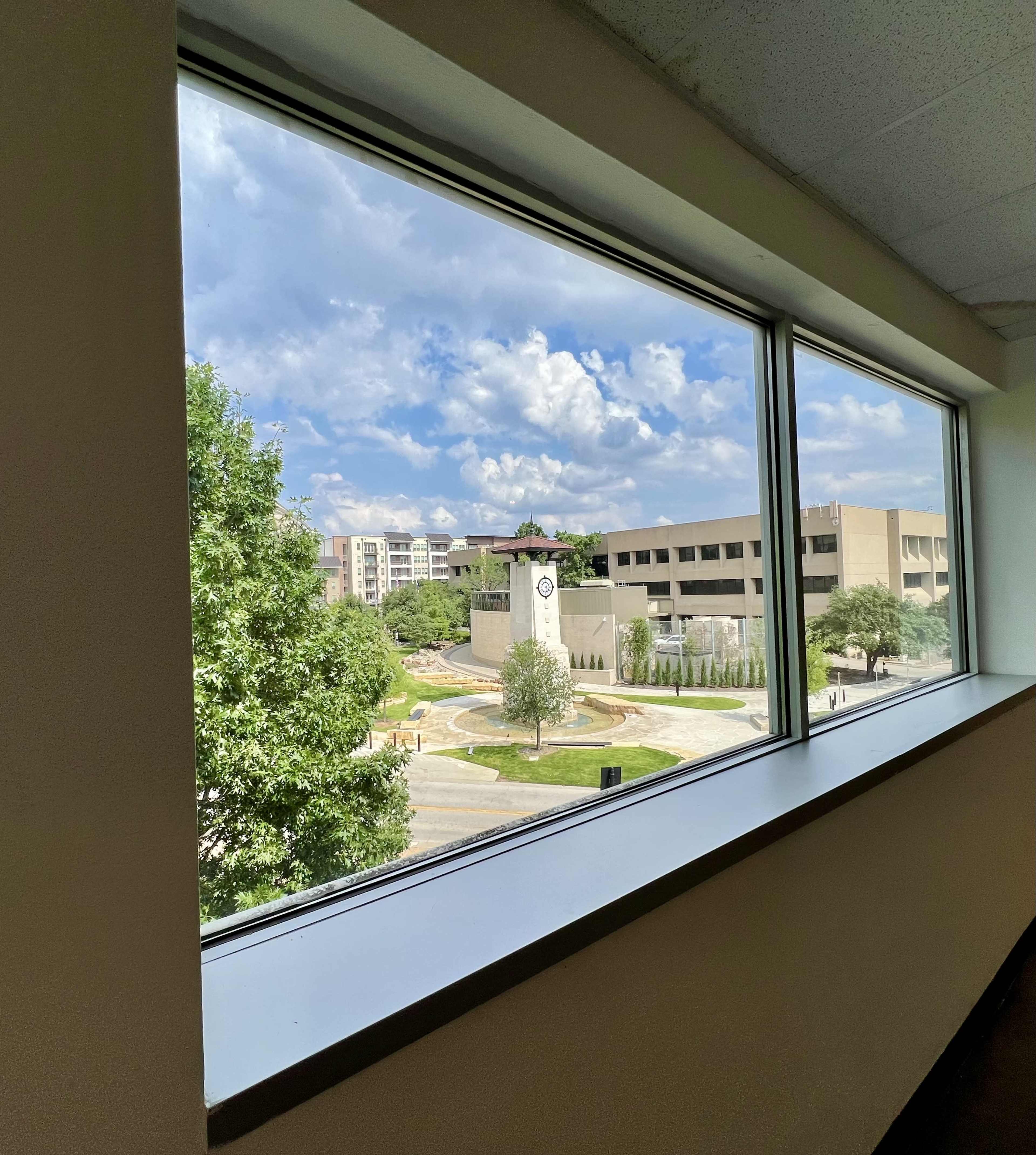 A view of a landscape with a clock tower and surrounding buildings, framed by a large window.
