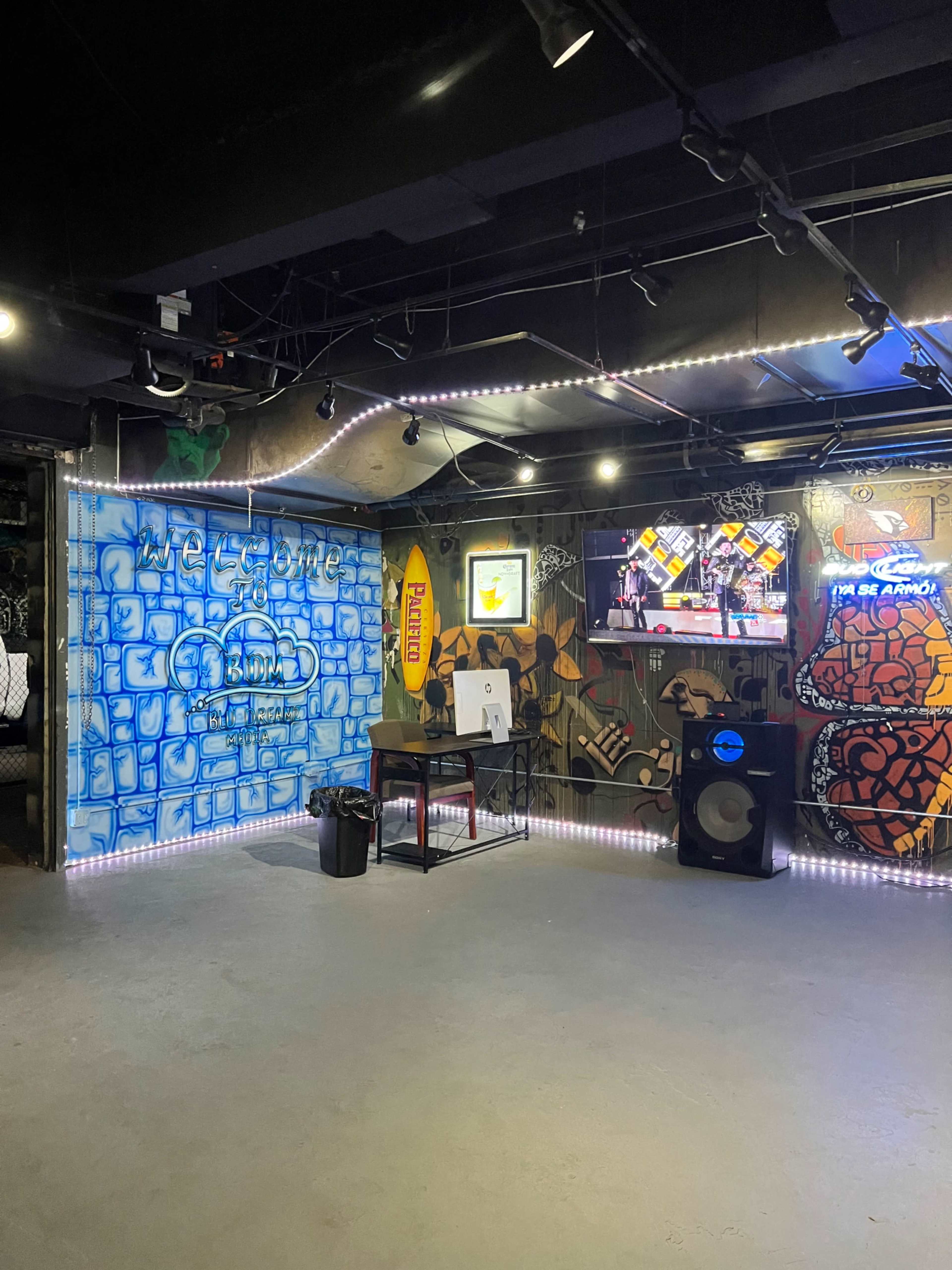 The image shows an urban space with graffiti-covered walls, a table, a speaker, and a television screen displaying graphics.