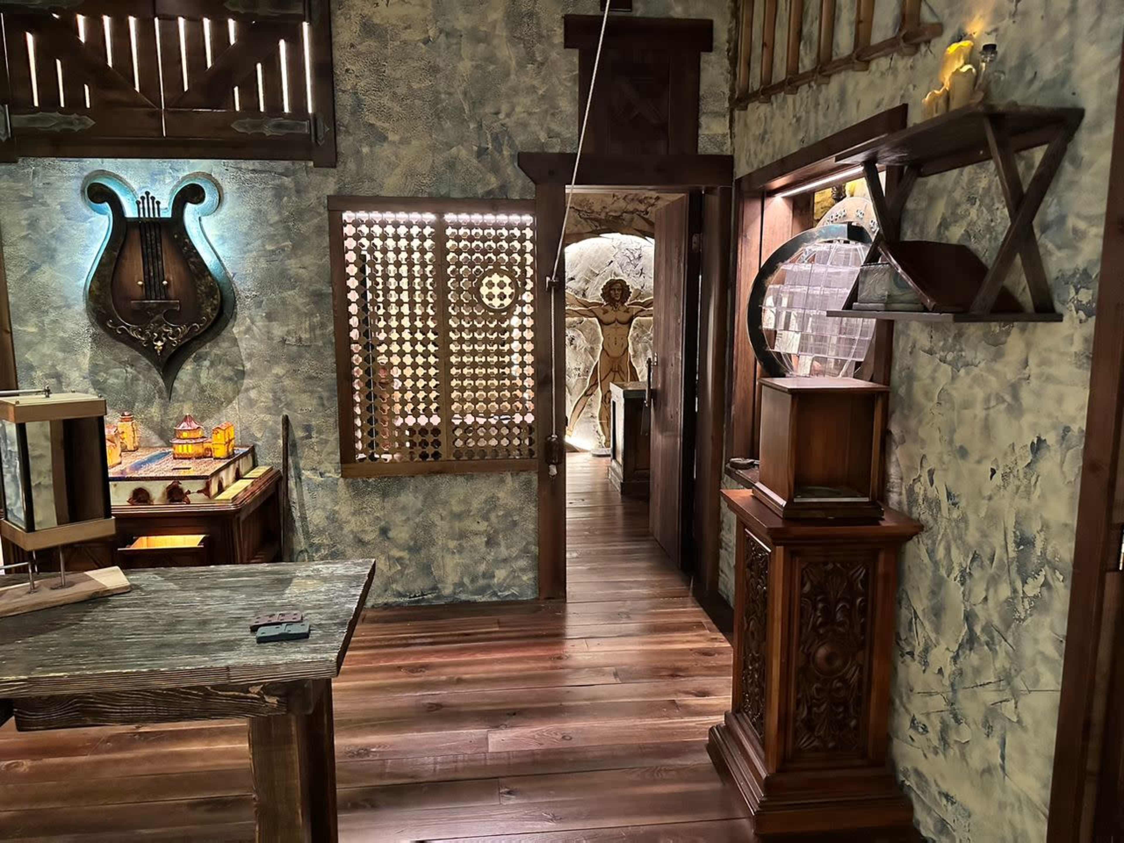 The image shows a well-decorated interior space featuring wooden furniture, textured walls, and a view through an archway into another room.