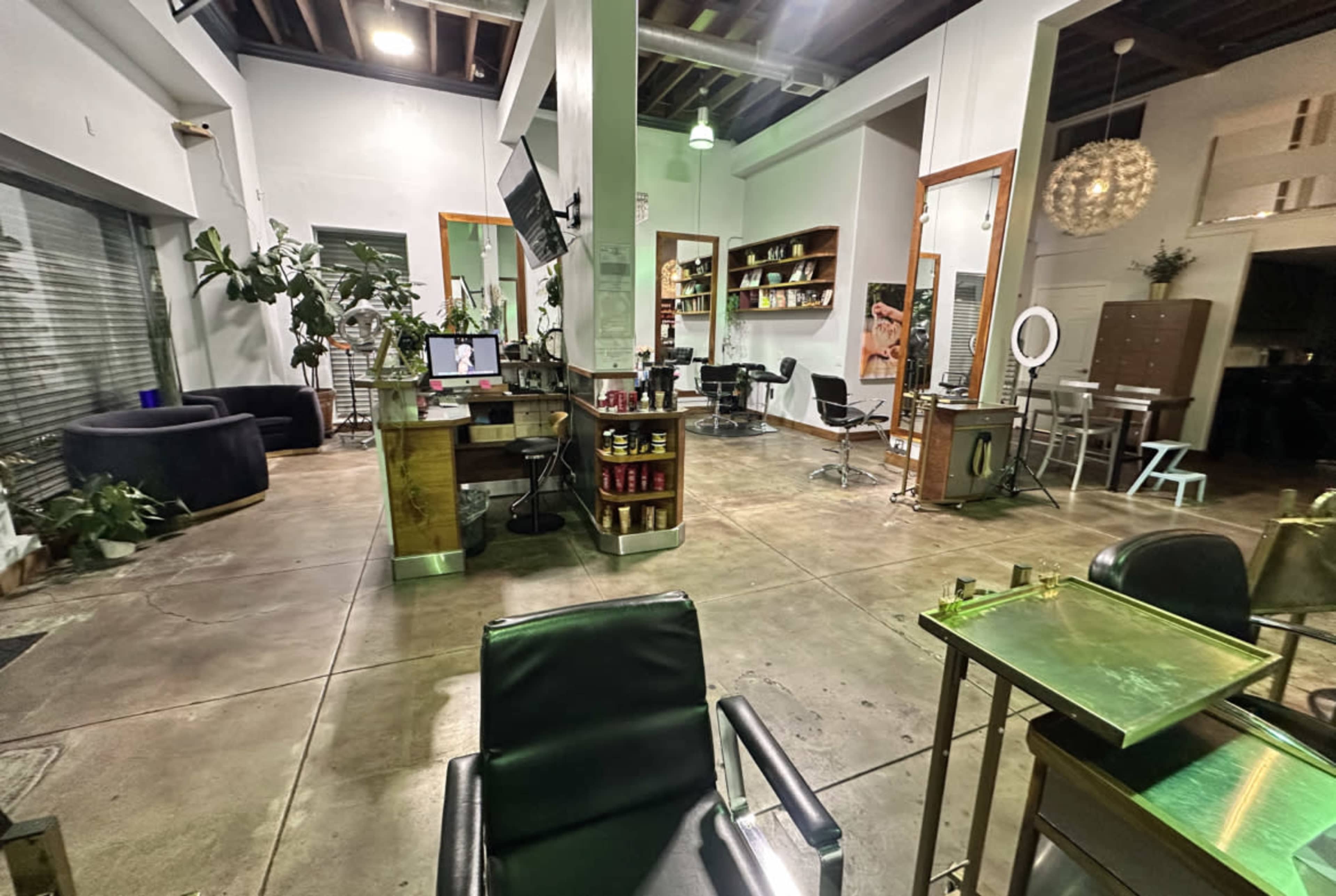 The image shows the interior of a hair salon featuring several styling stations, a reception area, and various furnishings set in a modern layout.