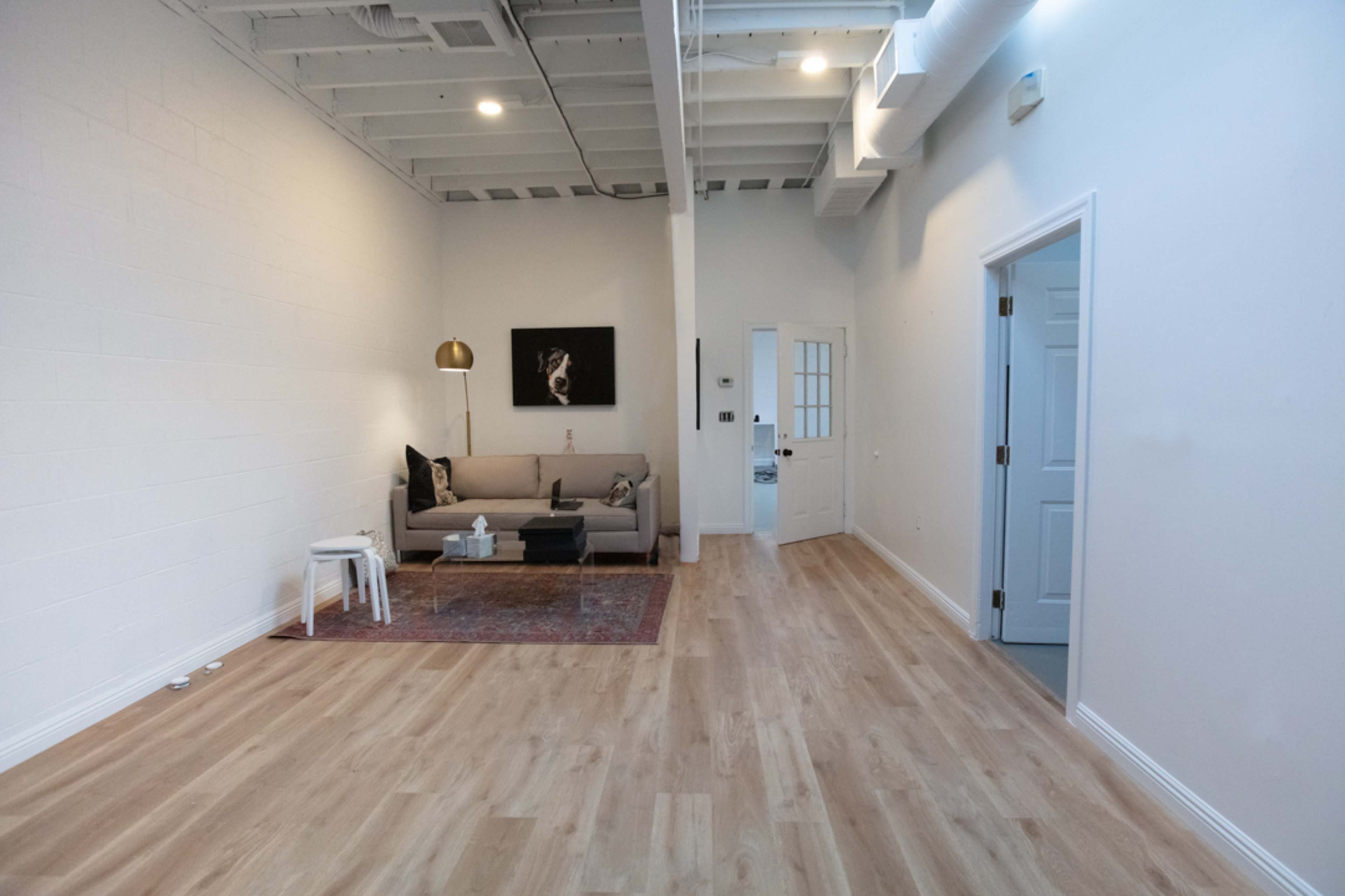 A spacious living area with a beige sofa, a coffee table, and a large wooden floor.