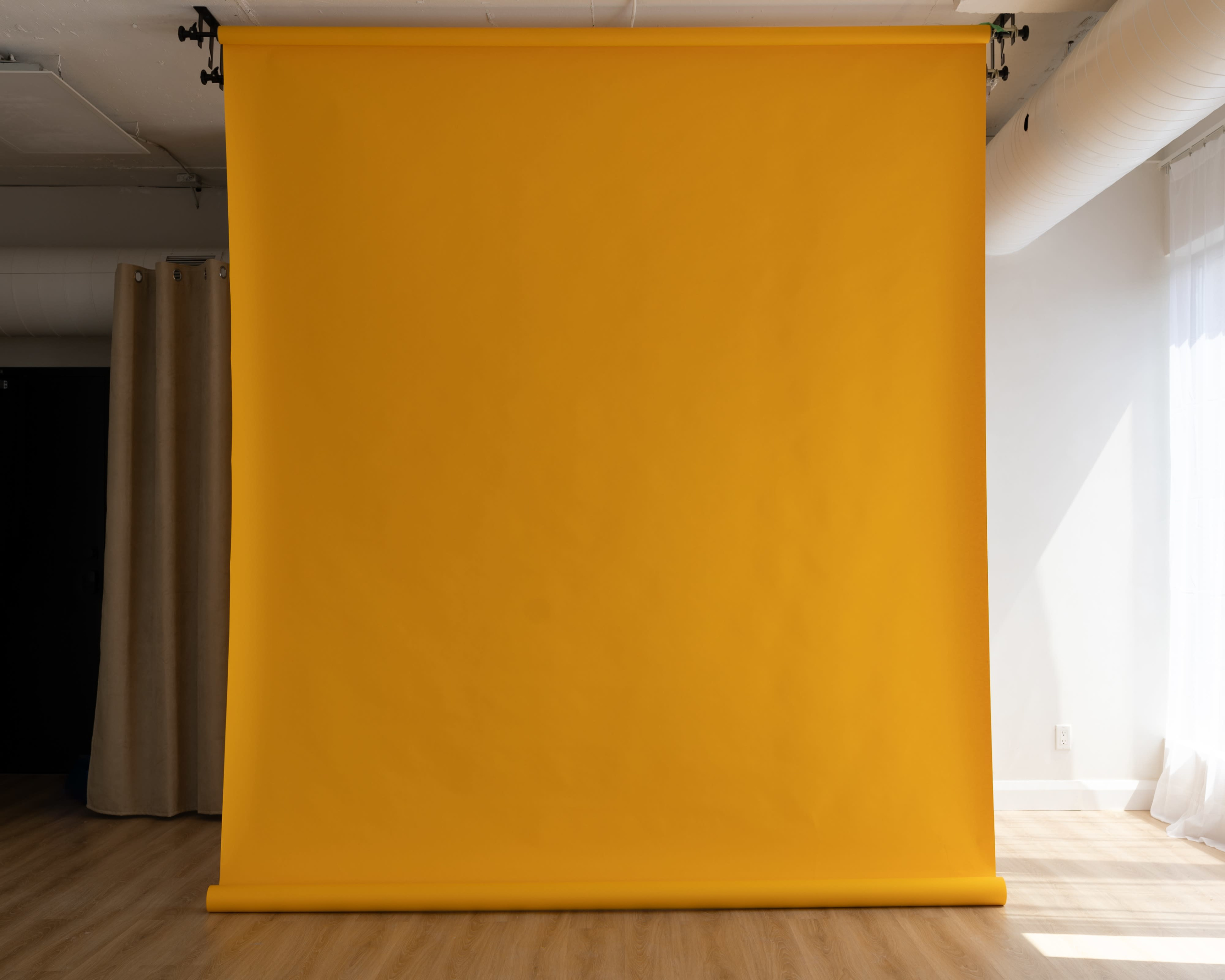 A large yellow backdrop is set up against a wall in a well-lit studio space.