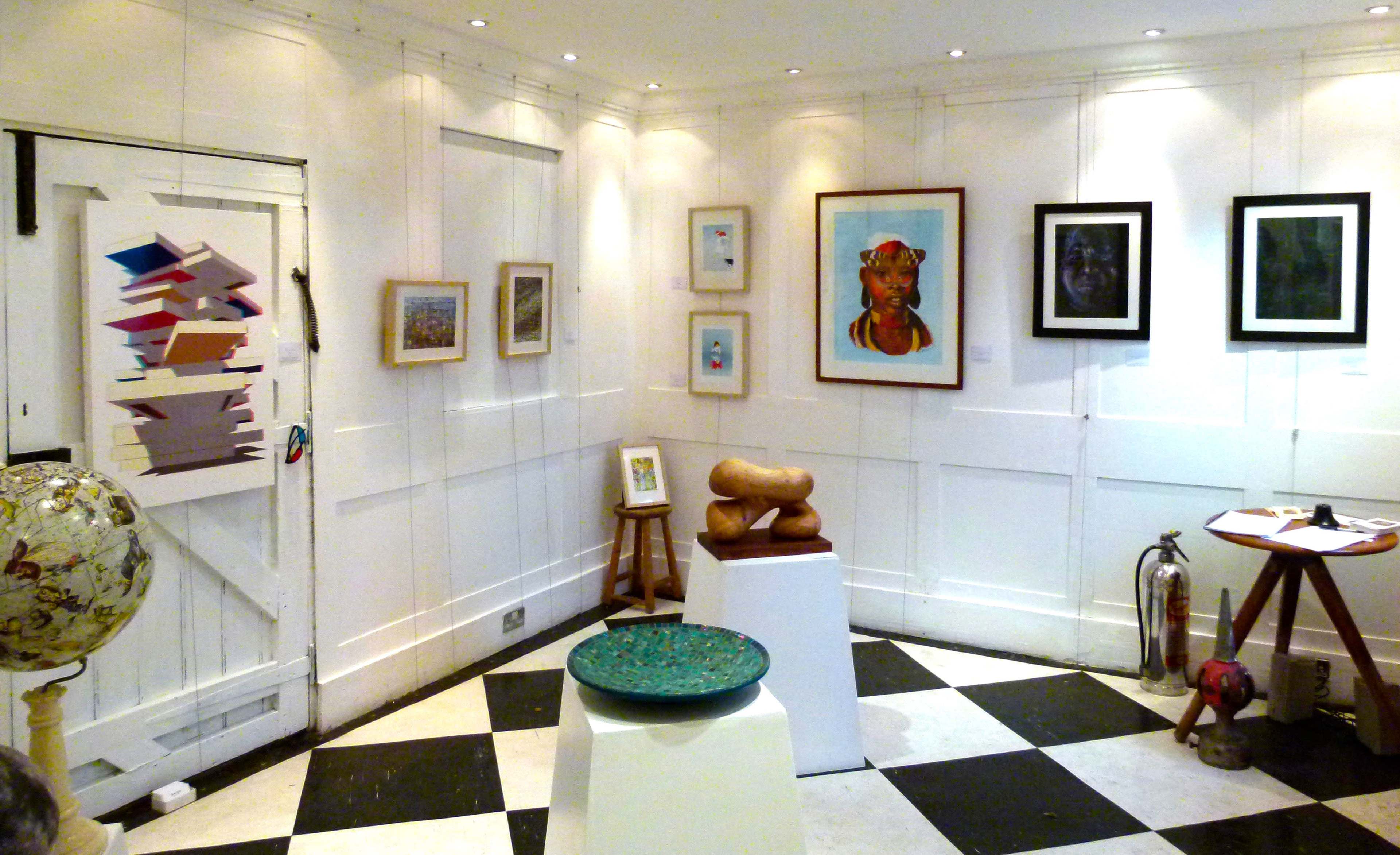An art gallery interior with various framed artworks displayed on white walls, a globe in the corner, and a mix of sculptures and tables on a black and white checkered floor.