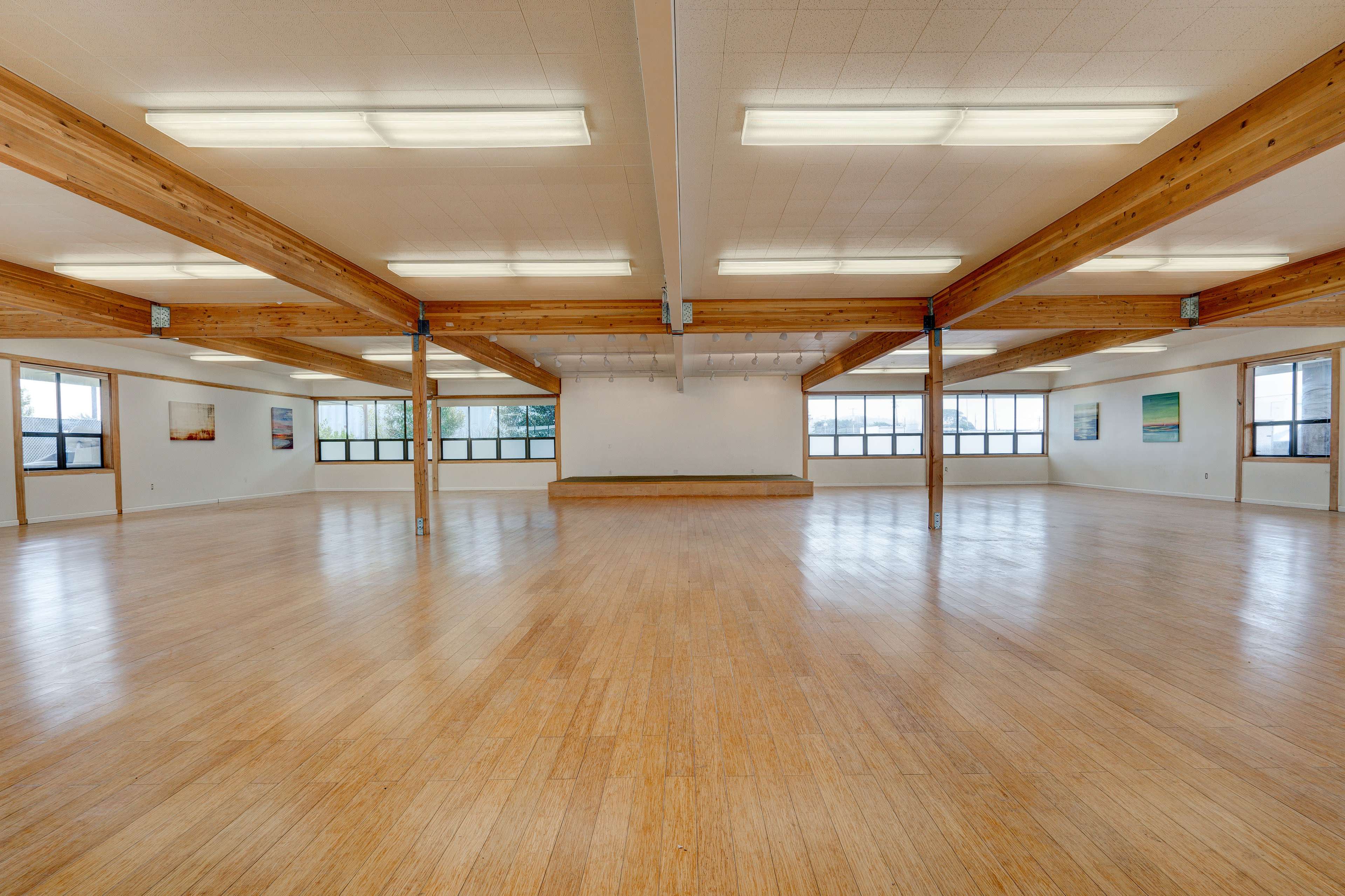 A spacious, empty dance studio with wooden beams and large windows.