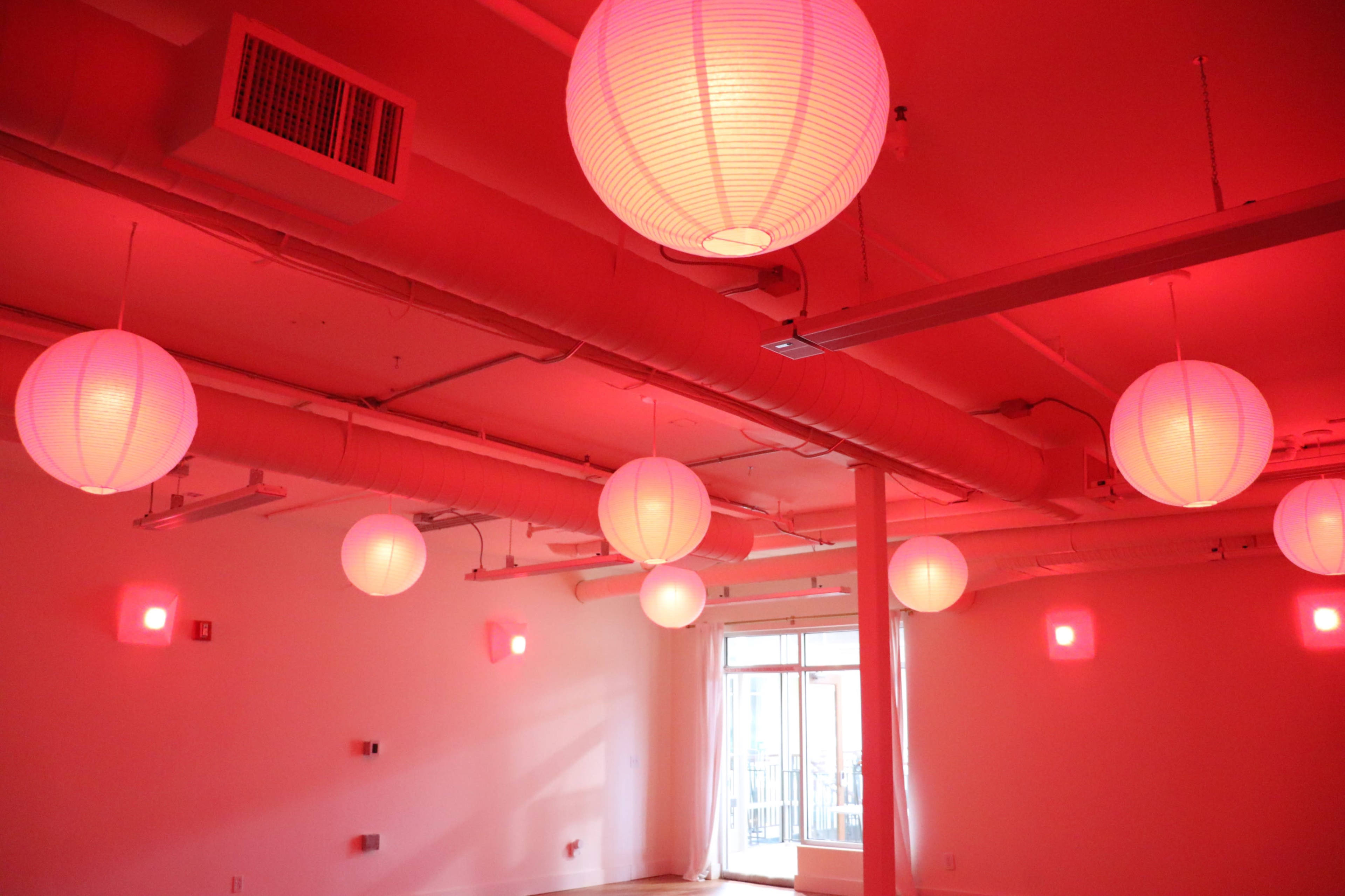 The image shows a room with multiple round paper lanterns hanging from the ceiling, illuminated with a red light.