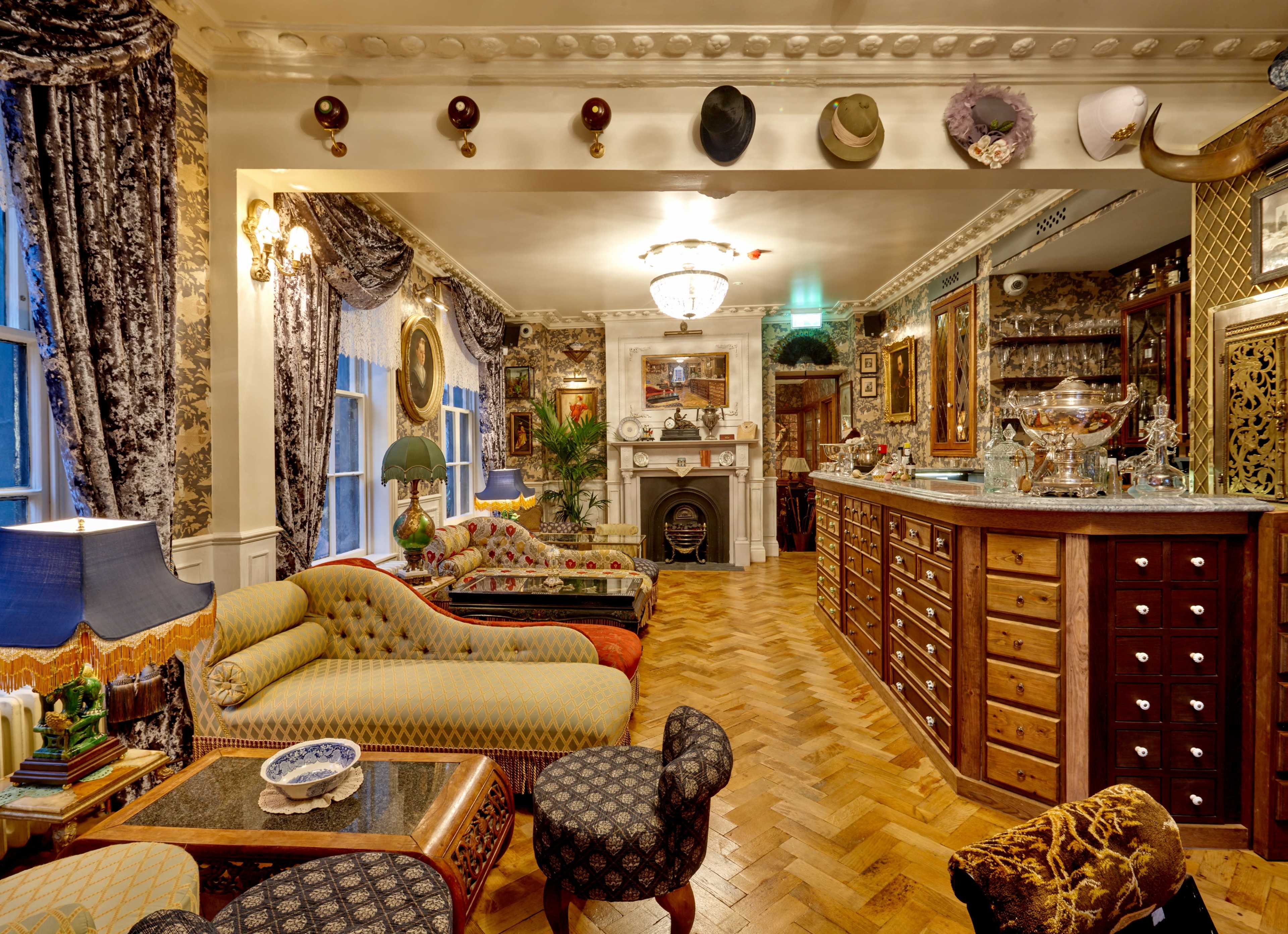 A lavishly decorated room with patterned upholstery, a wooden bar, and various decorative items, including hats and artwork on the walls.