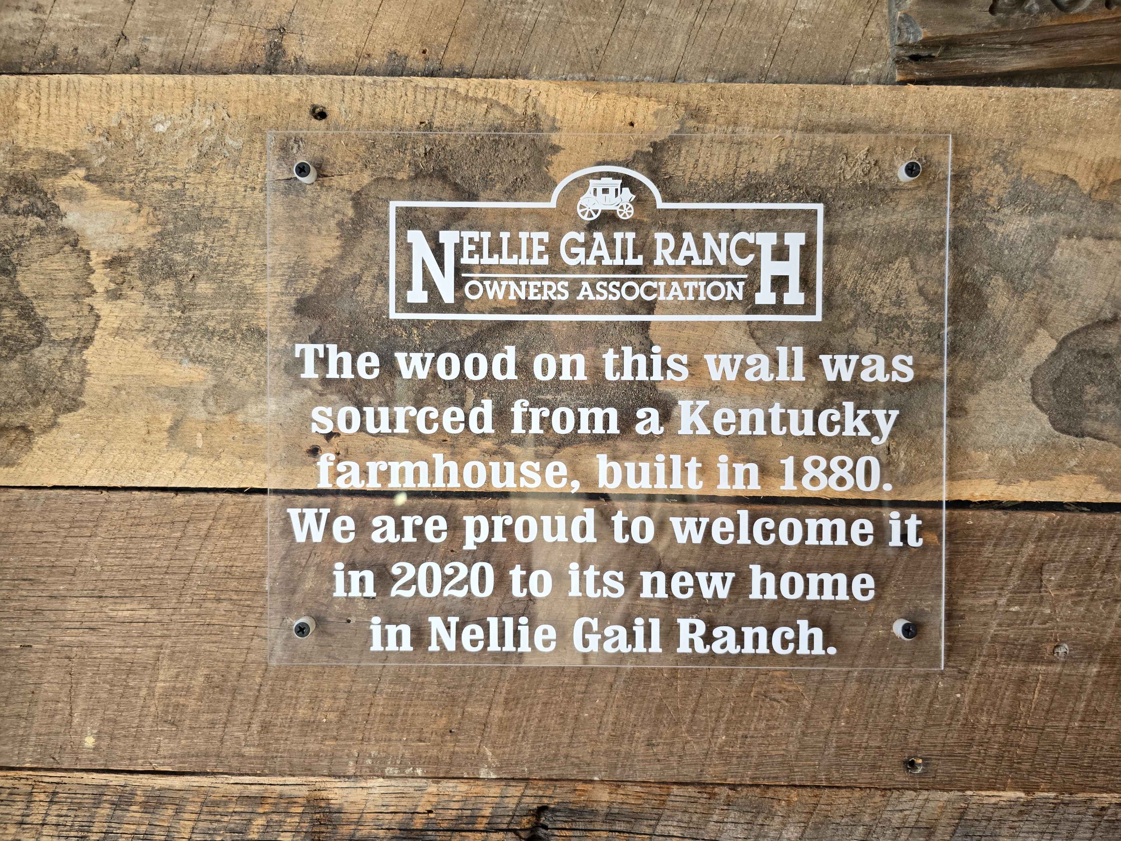 A clear sign on a wooden wall states that the wood was sourced from a Kentucky farmhouse built in 1880 and is now in Nellie Gail Ranch as of 2020.