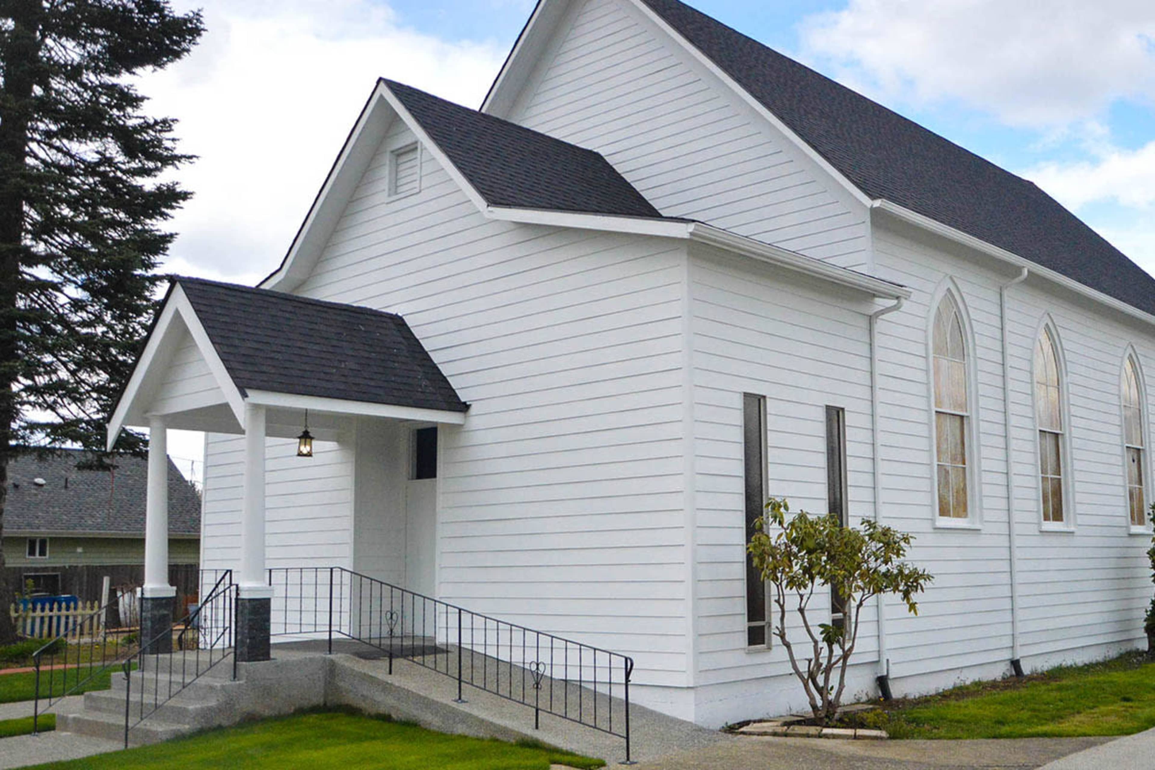 A white church building with a gabled roof, a small entrance porch, and a well-maintained ramp leading to the entrance.