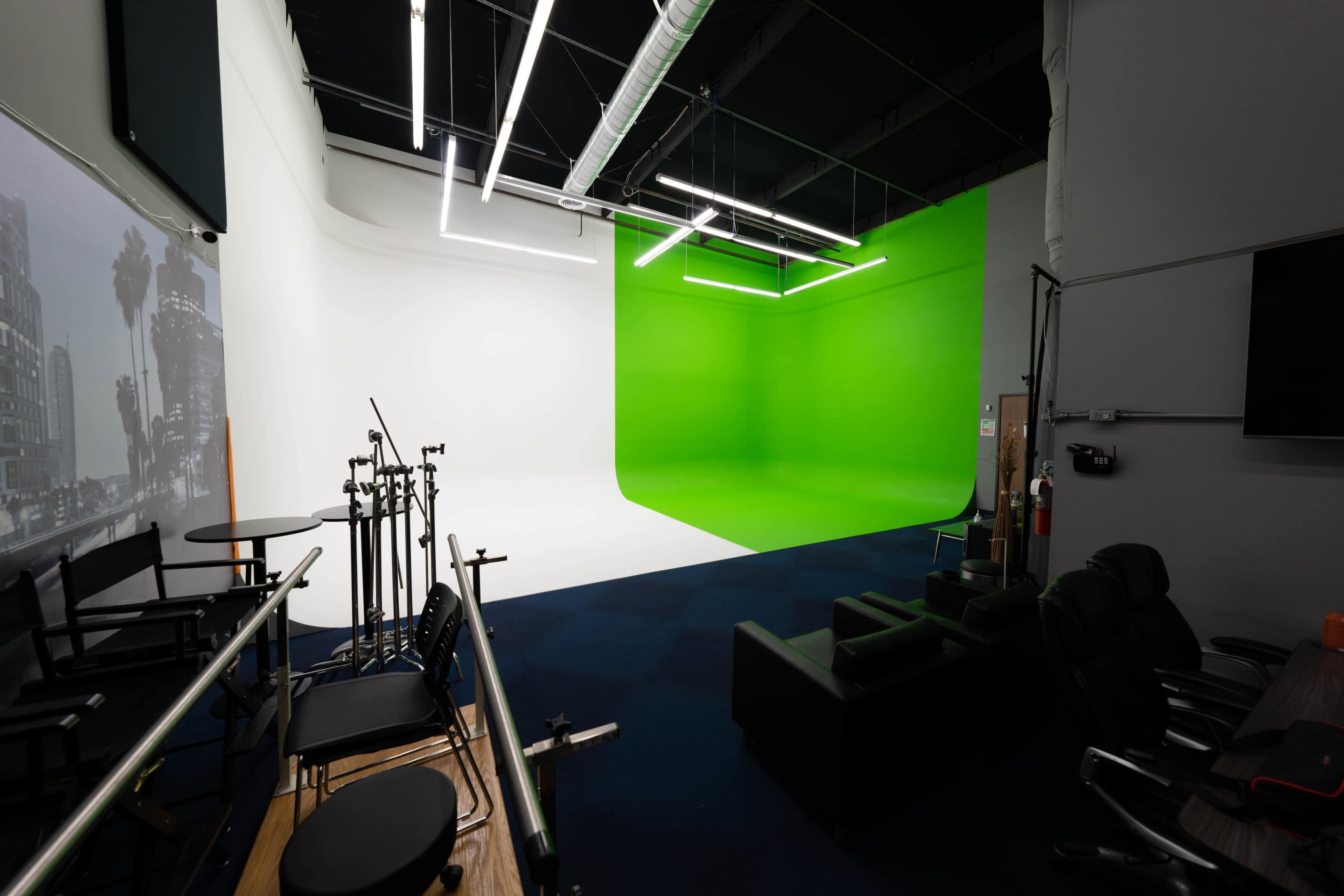 The image shows a photography studio equipped with green and white backdrops, along with several lighting and camera stands.