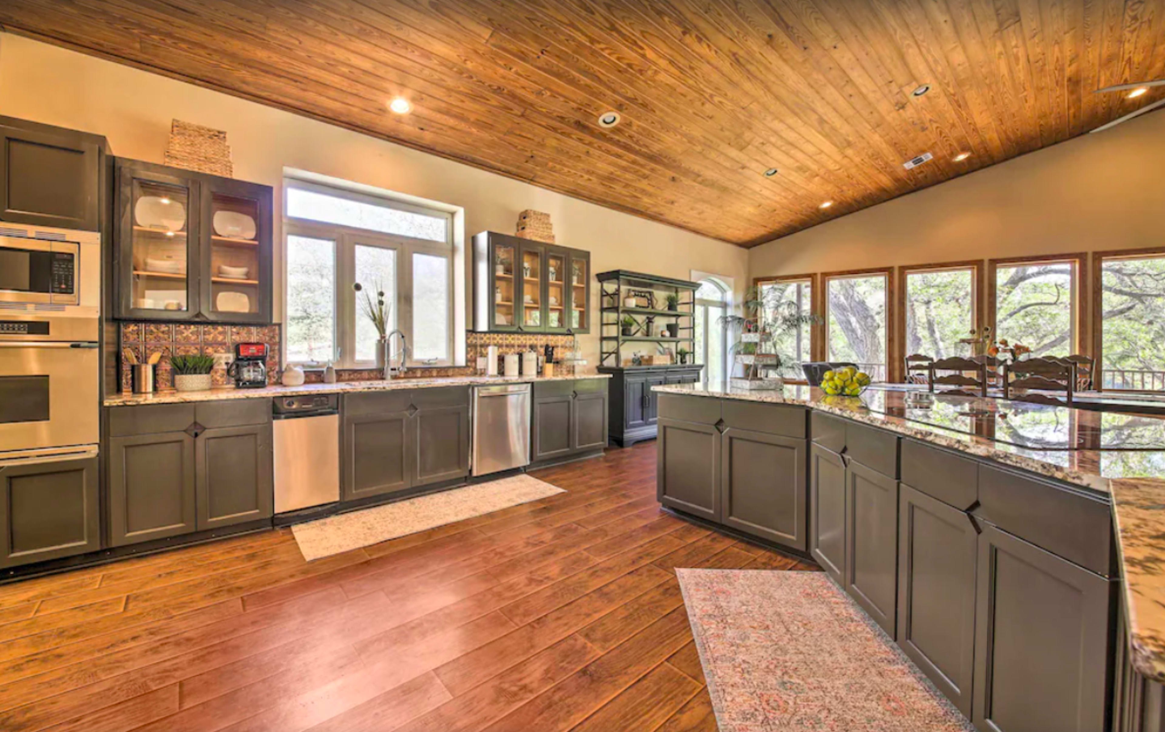 A spacious kitchen with dark cabinets, stainless steel appliances, and large windows that provide natural light.