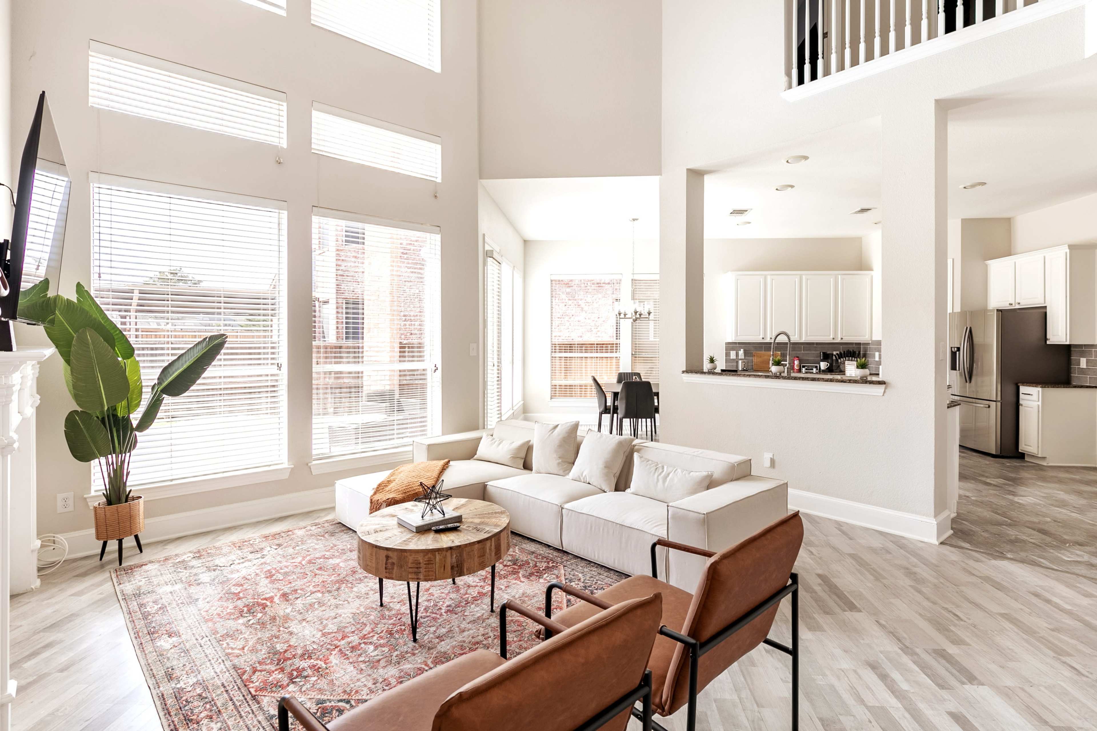 A spacious living area with large windows, modern furniture, and a decorative area rug.