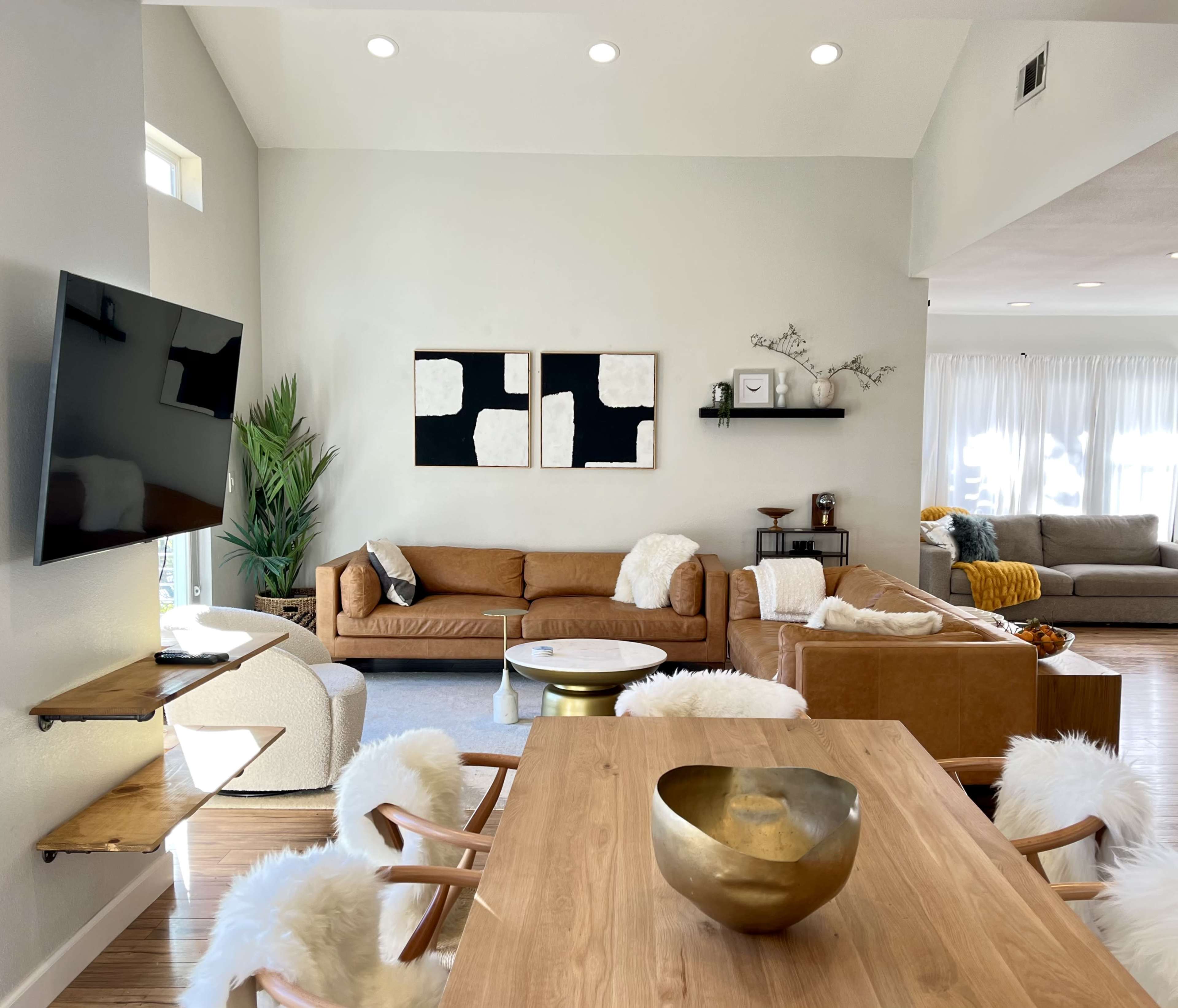 A spacious living room with a mix of leather and fabric sofas, wooden furniture, and decorative art on the walls.