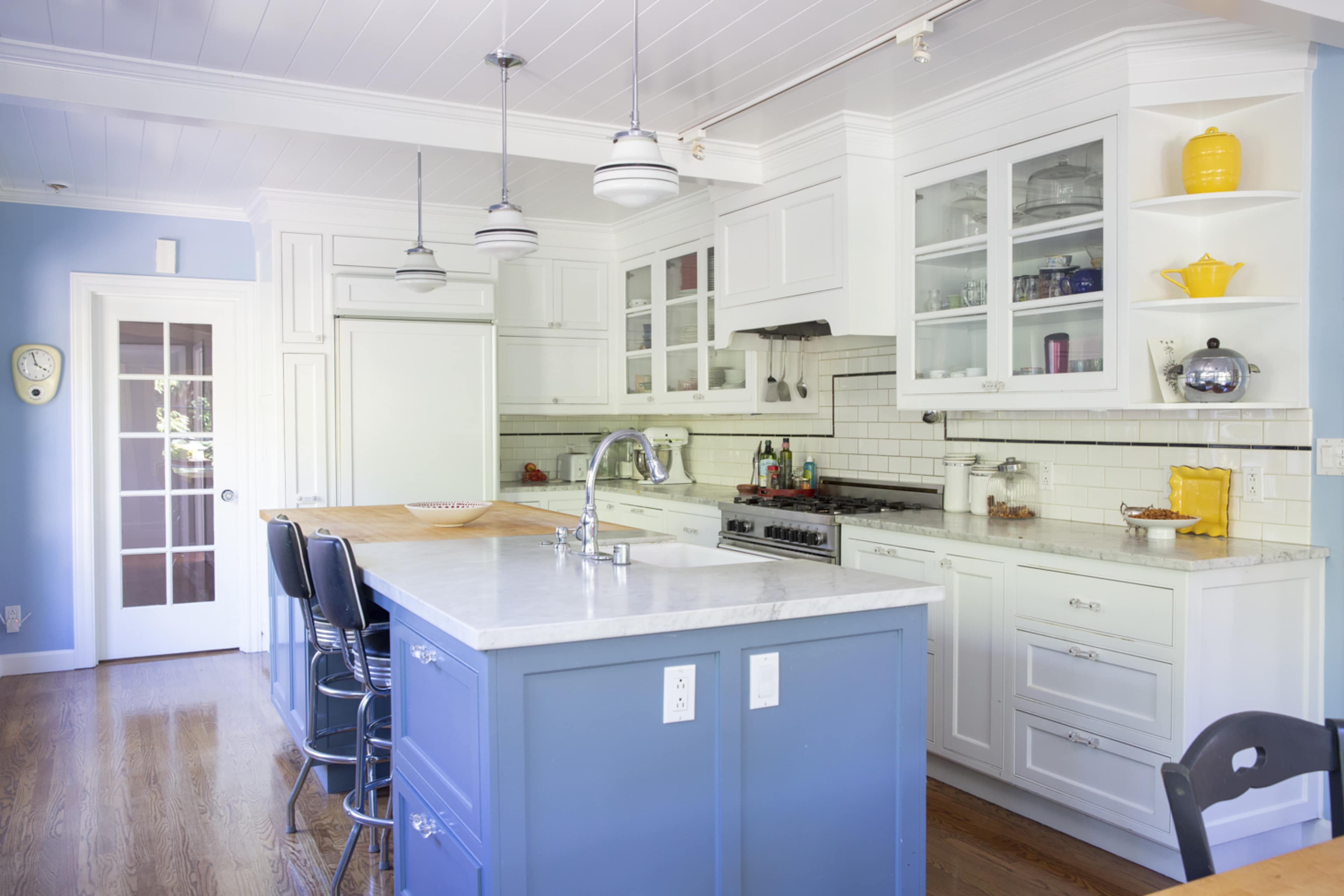 A modern kitchen with a central island, white cabinetry, and blue accent walls.