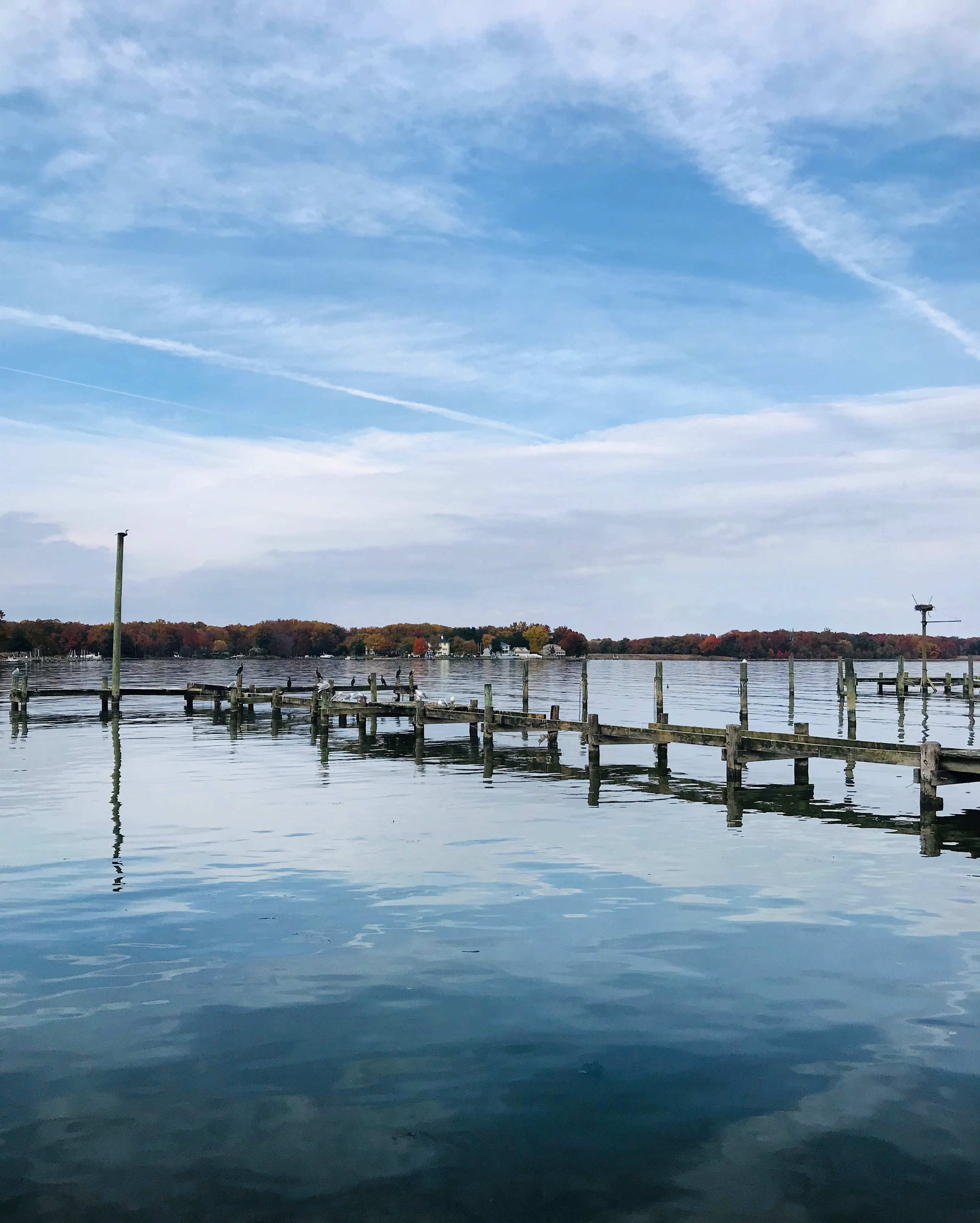A calm lake with a wooden dock extending into the water under a cloudy sky.