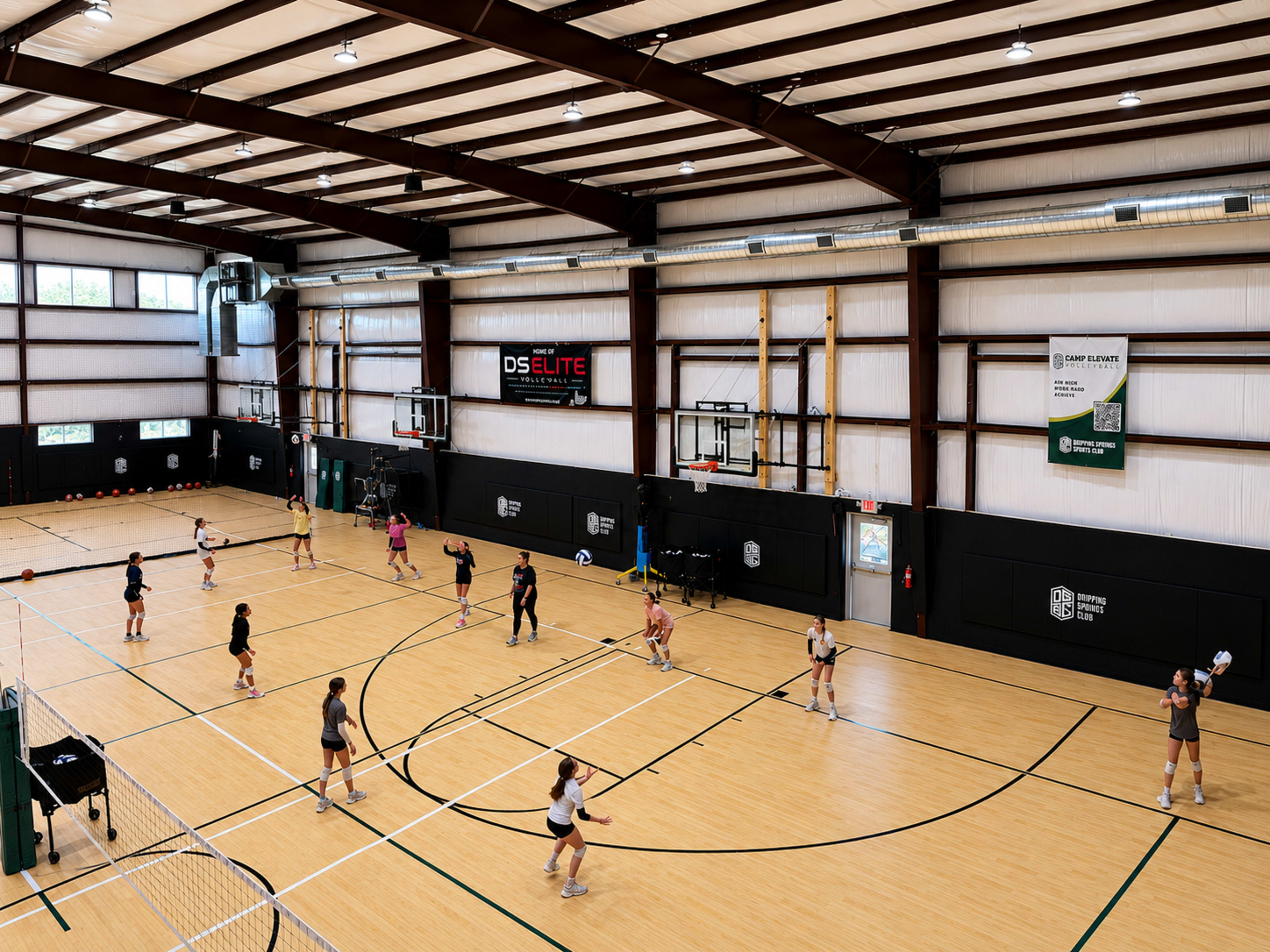 The image shows a large indoor sports facility with multiple volleyball courts, where several groups of players are practicing.
